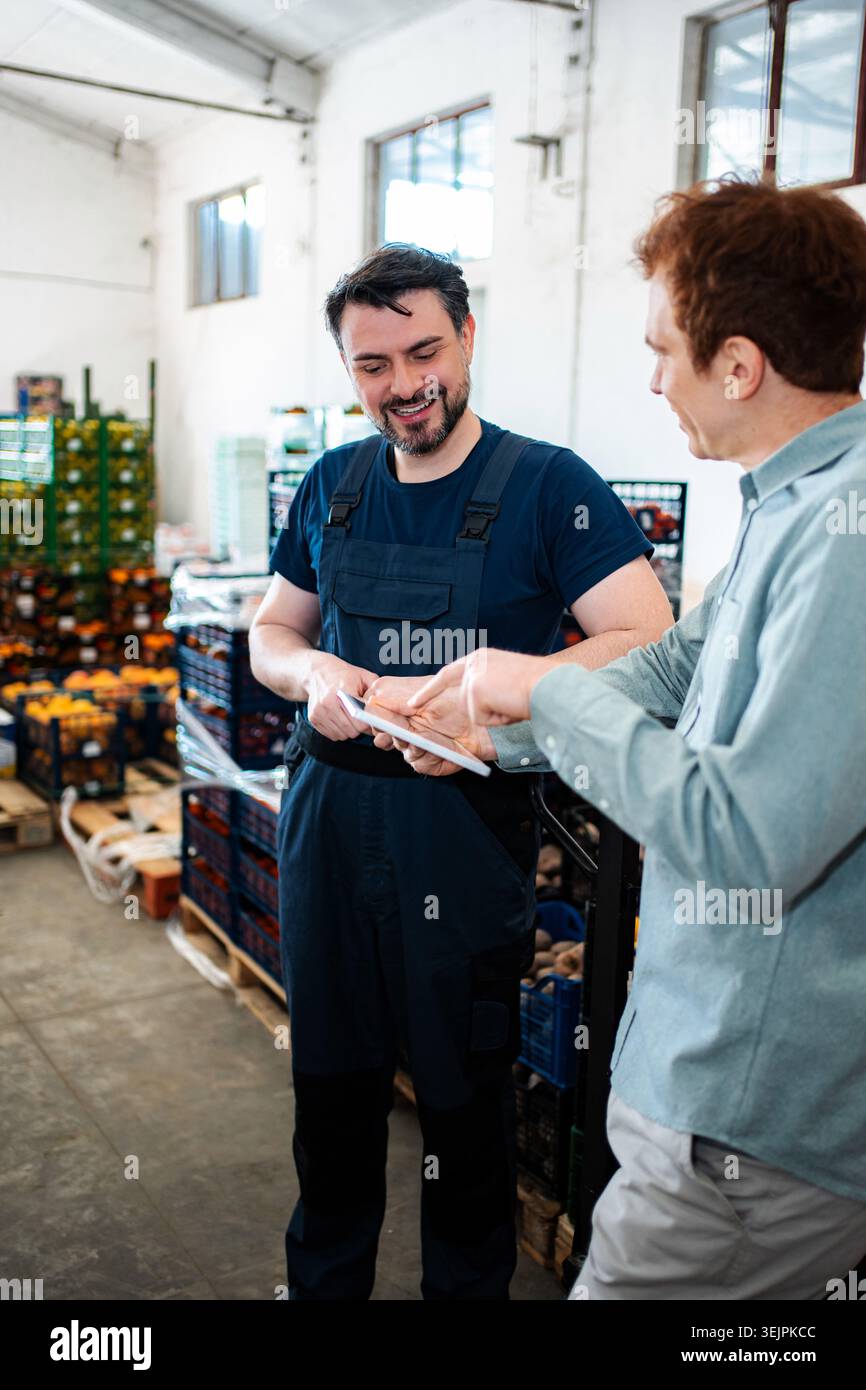 Warehouse worker and manager discussing inventory using digital tablet Stock Photo