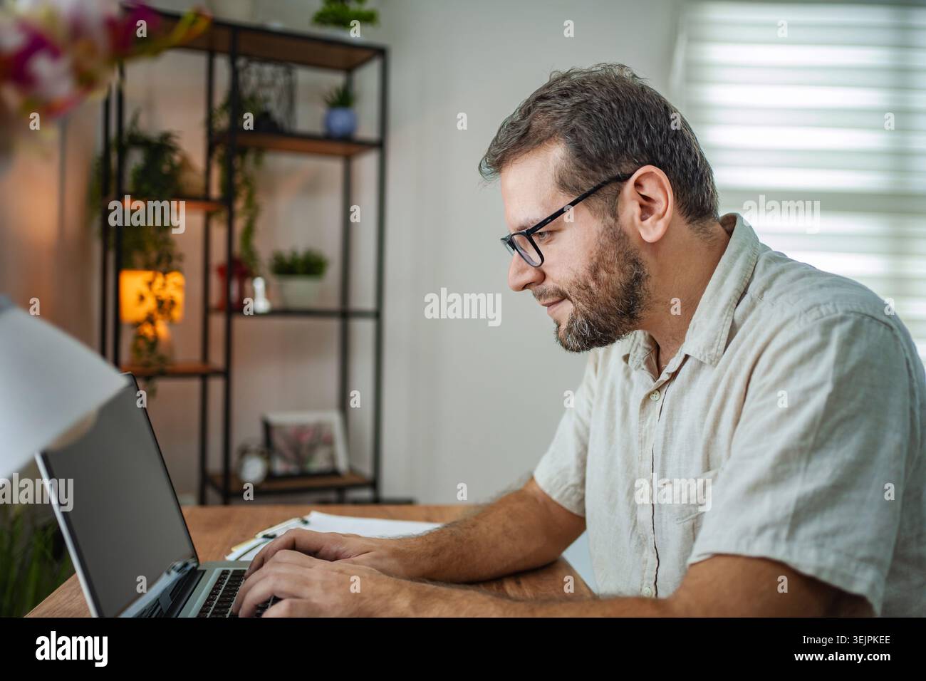 Focused man working on his laptop in a cozy workspace Stock Photo