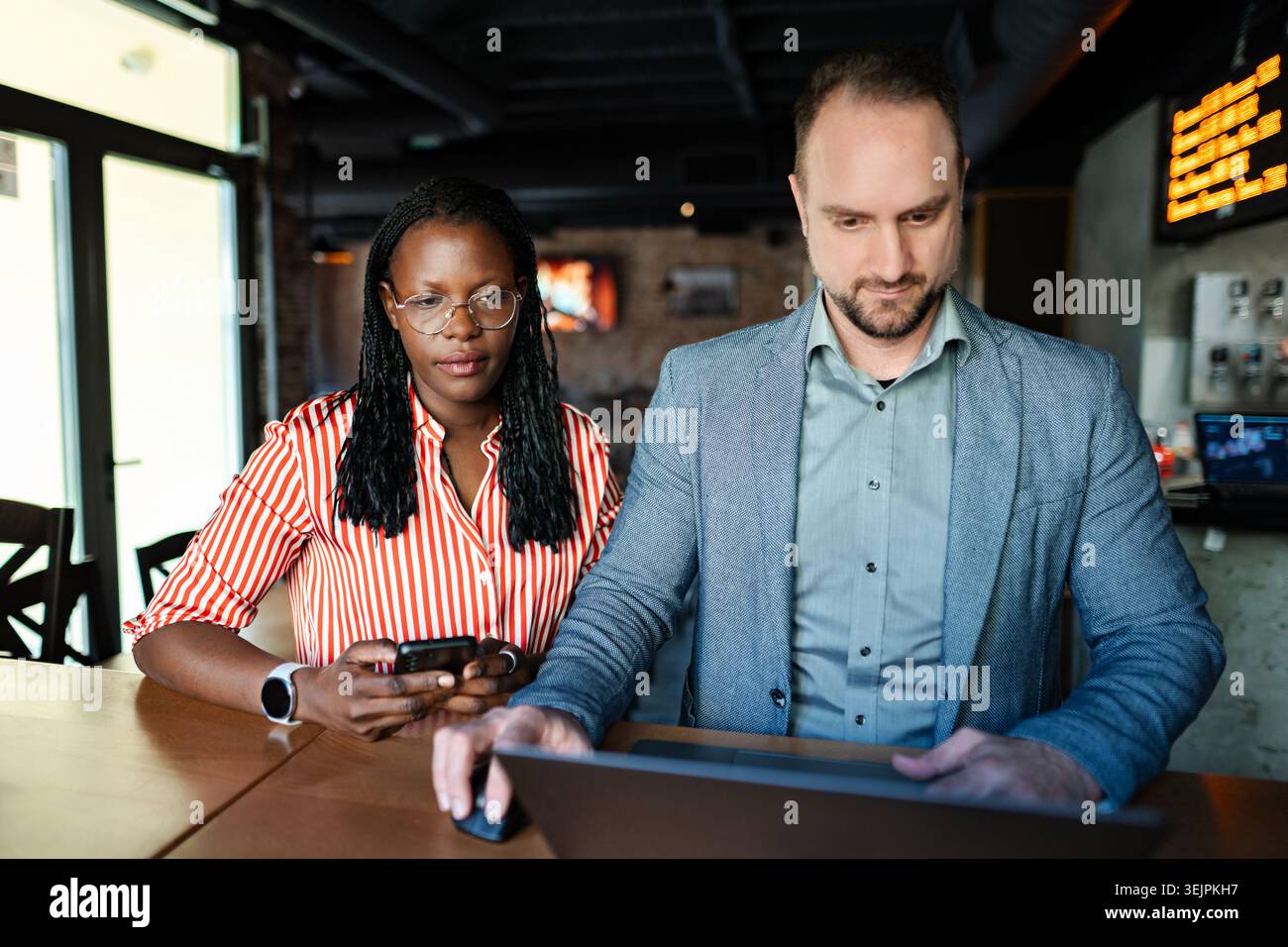 Diverse business partners collaborating digitally using laptop and phone Stock Photo