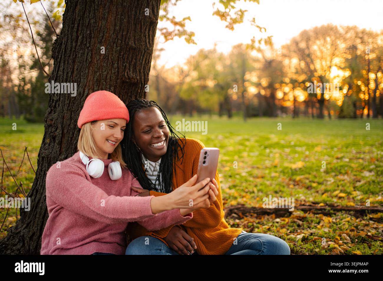 Diverse friends taking a selfie using smartphone in autumn park Stock Photo