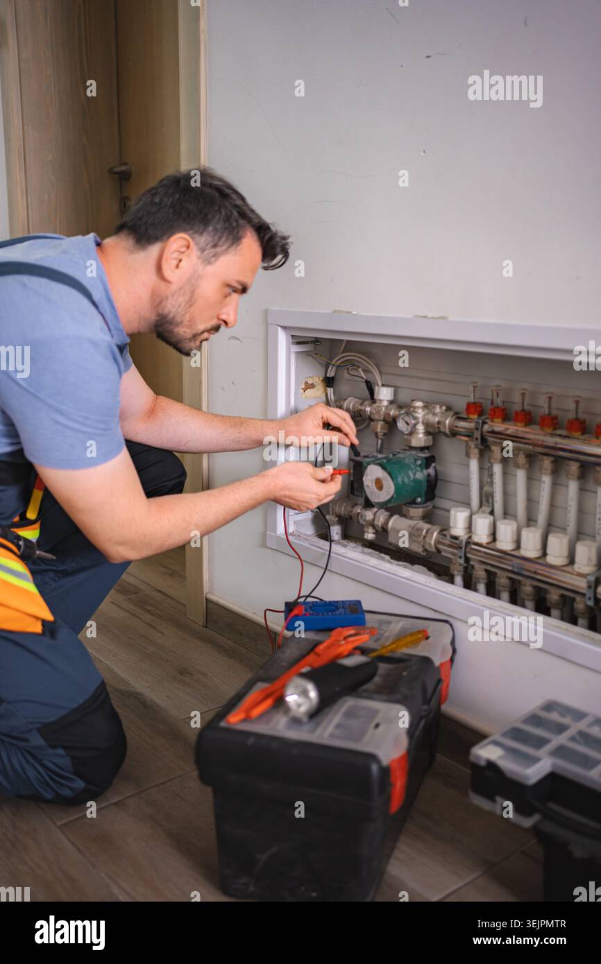 Technician checking domestic heating system with multimeter Stock Photo