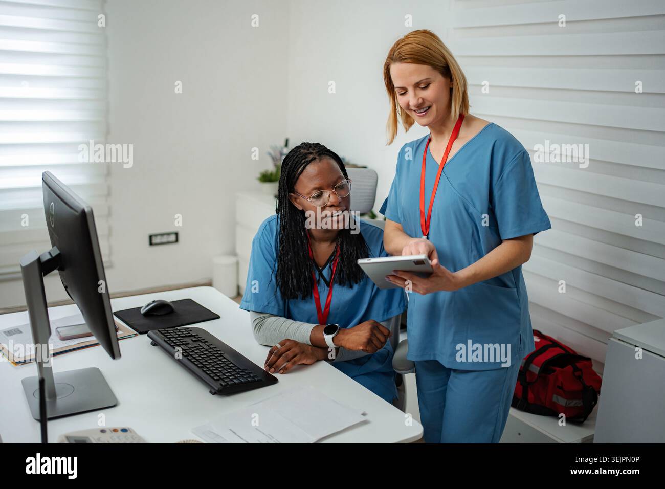 Nurses collaborating on digital tablet in modern medical office Stock Photo