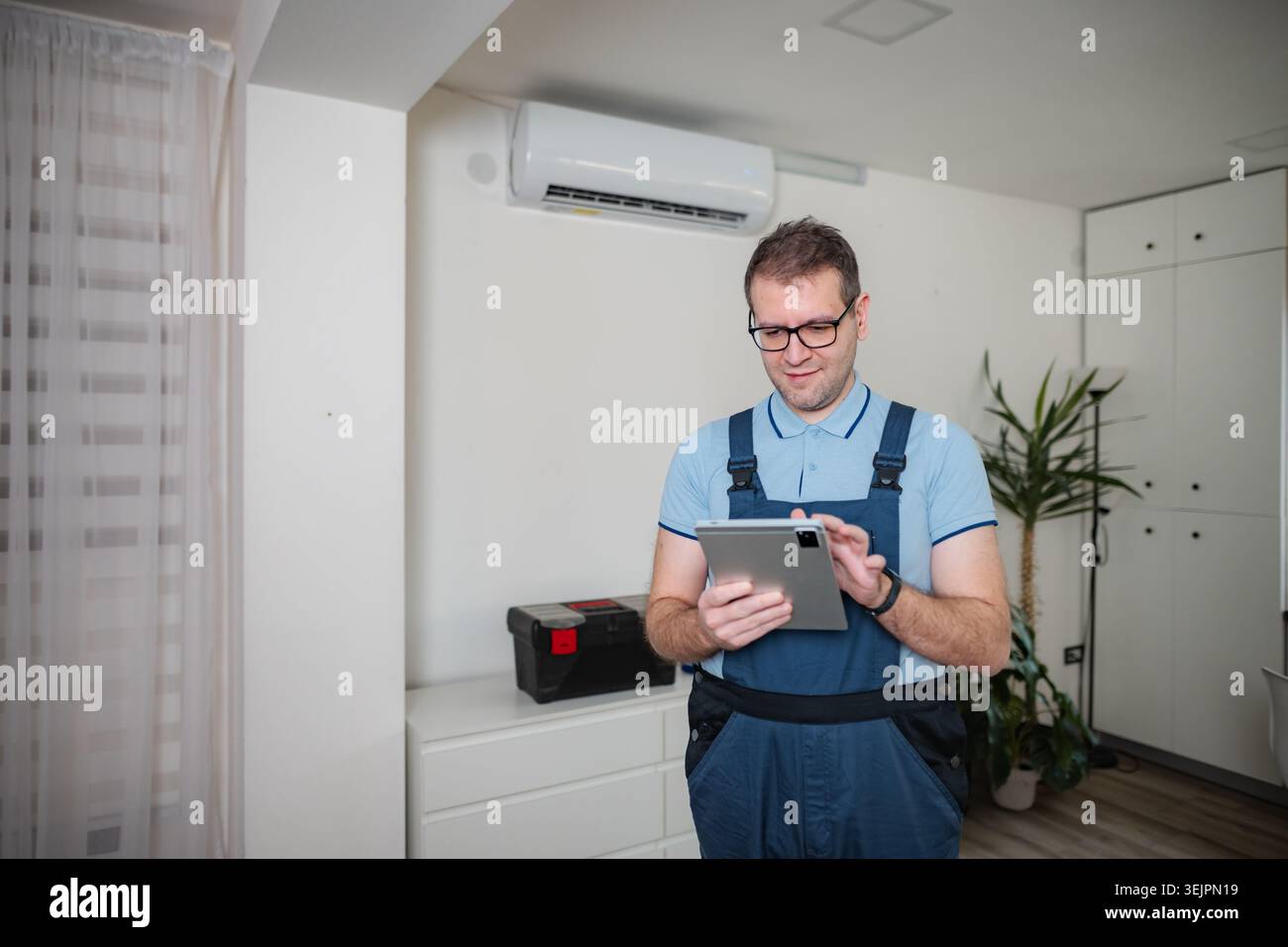 HVAC technician checking air conditioner using digital tablet Stock Photo