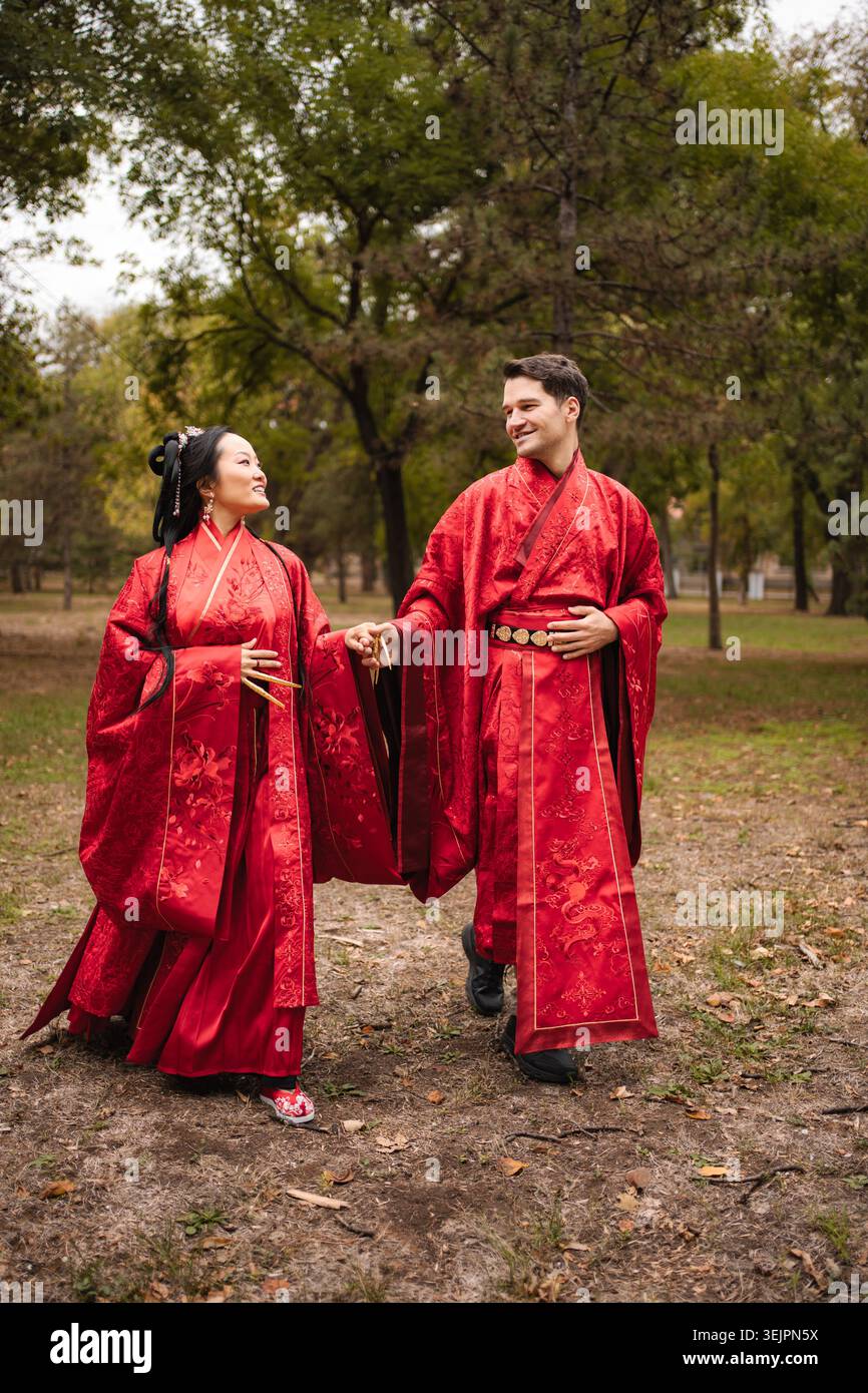 Multicultural wedding couple holding hands in traditional clothing Stock Photo