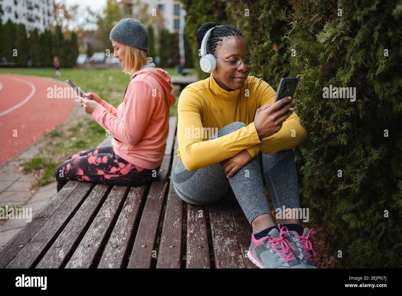 Two women using smartphones ignoring each other in park Stock Photo