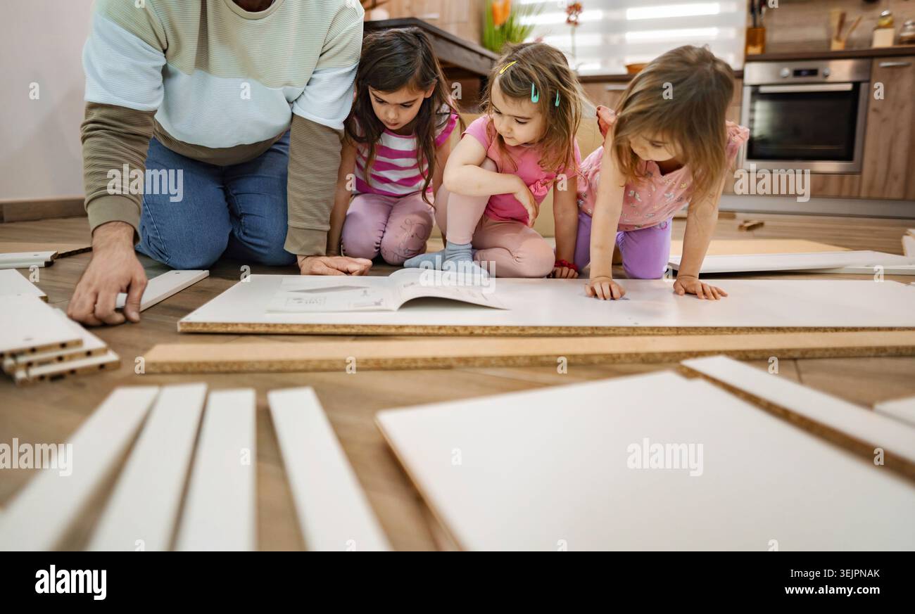 Children engaged in creative assembly in a cozy kitchen space Stock Photo