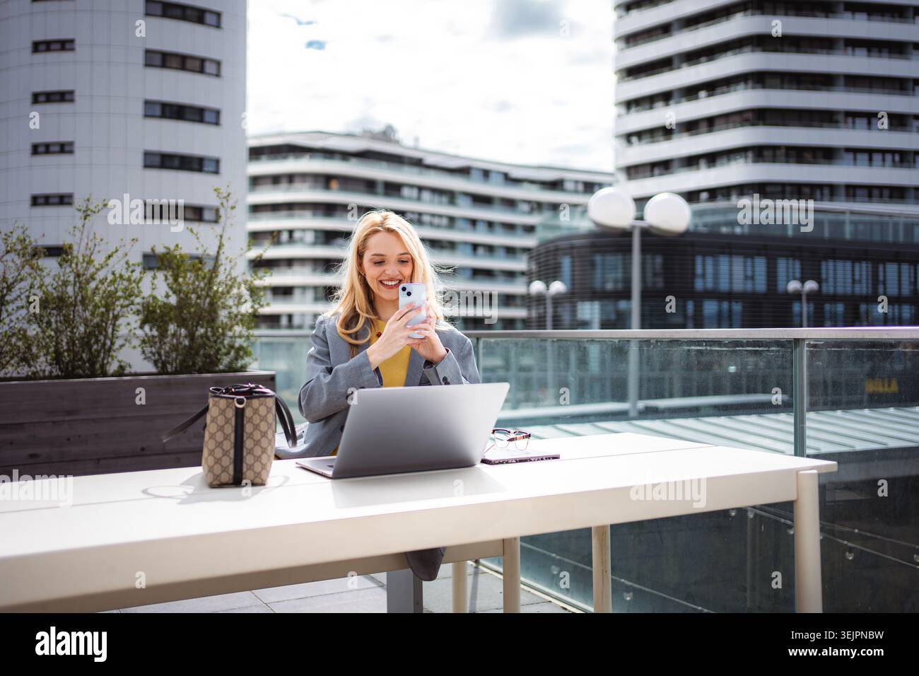Young businesswoman using smartphone and laptop for remote work Stock Photo