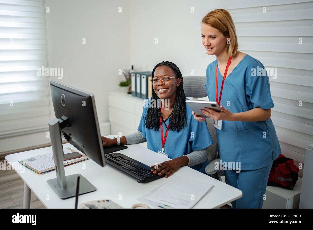 Diverse medical workers collaborating on computer and digital tablet Stock Photo