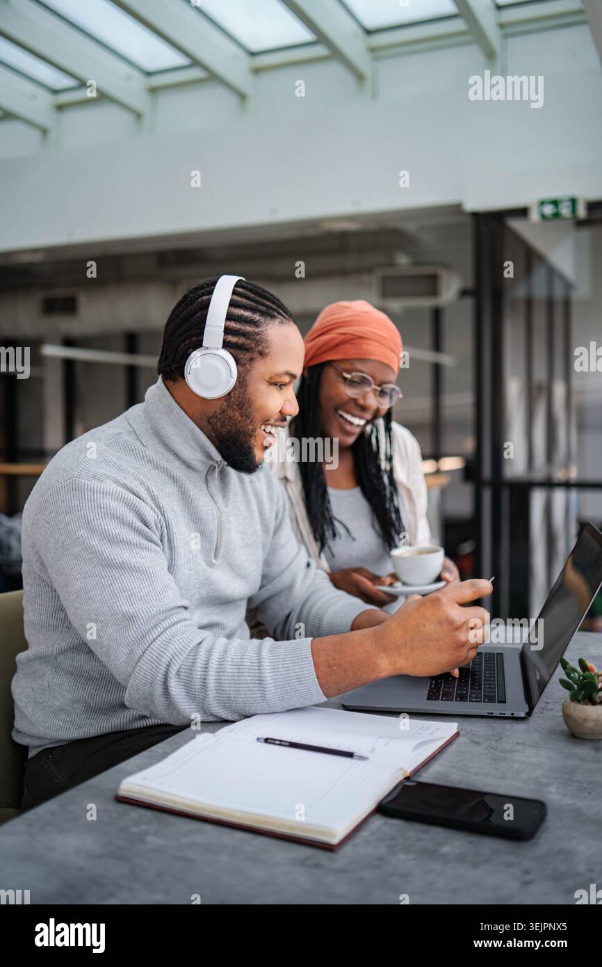 Colleagues collaborating on laptop while smiling and working in office Stock Photo