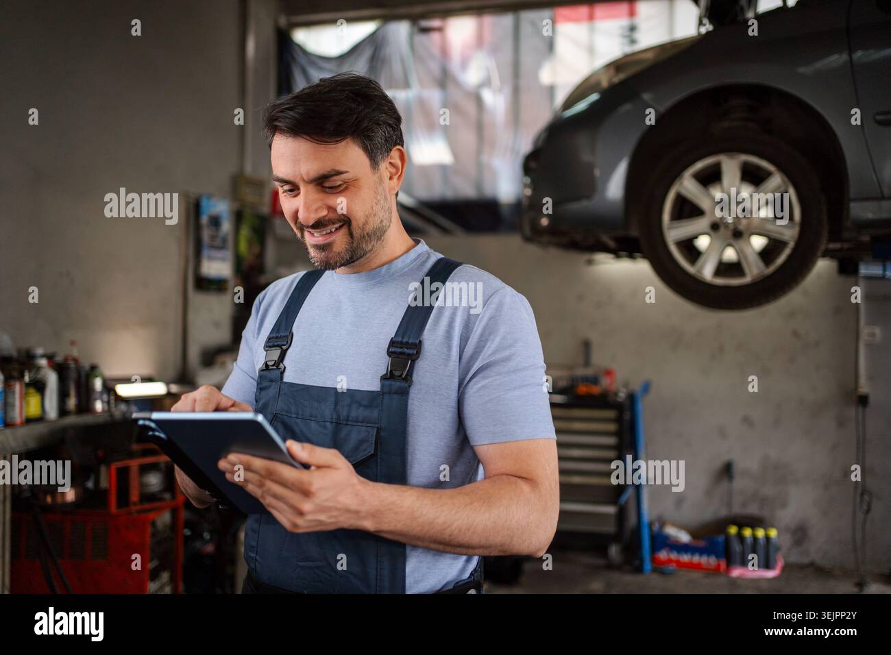 Car mechanic using a tablet in a workshop while smiling Stock Photo