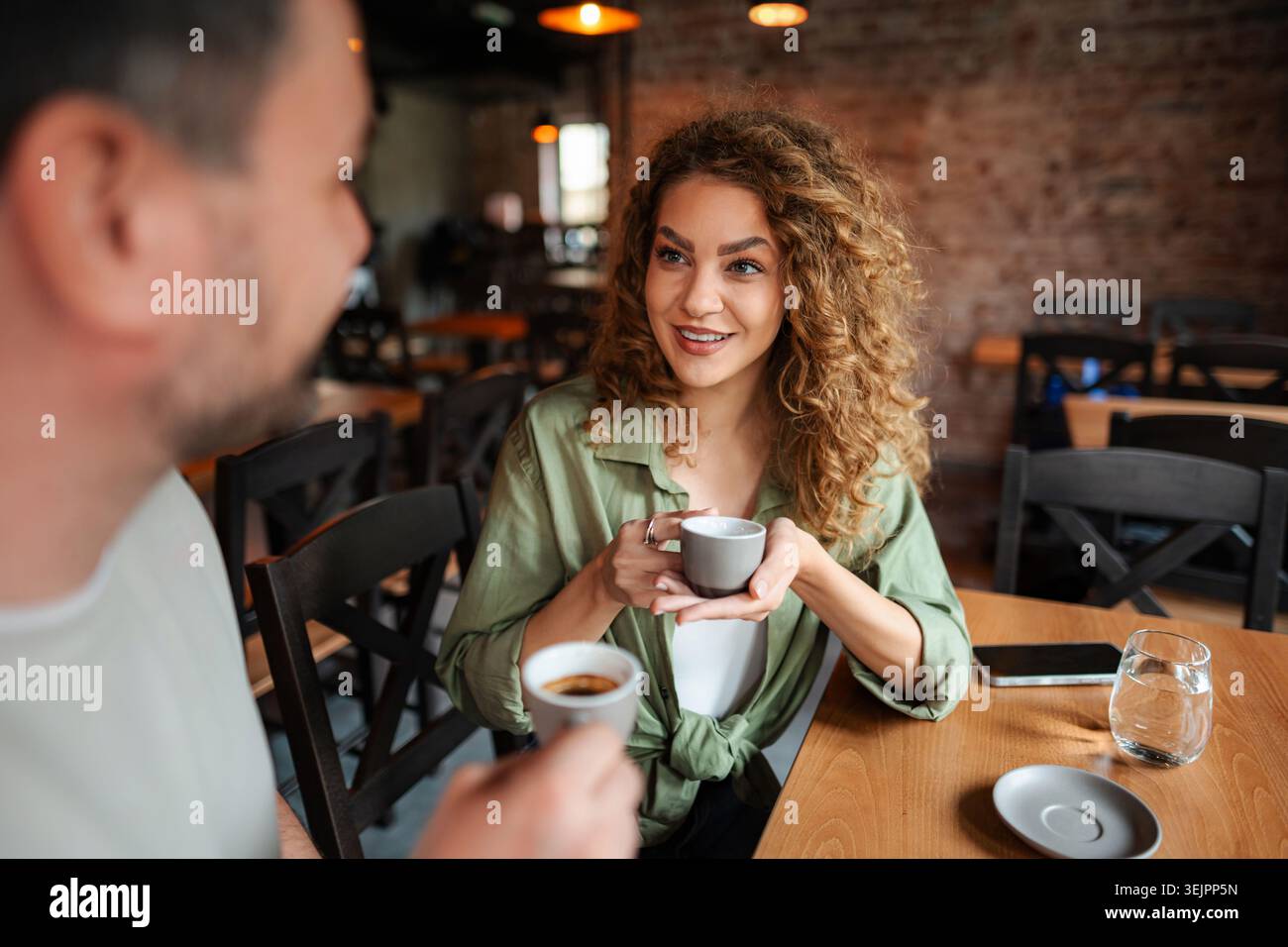 Young couple drinking coffee and talking at a cafe Stock Photo