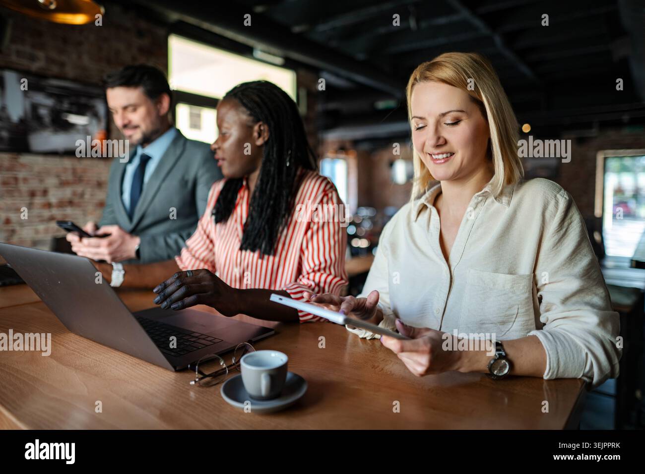 Diverse business team collaborating using technology in a cafe Stock Photo
