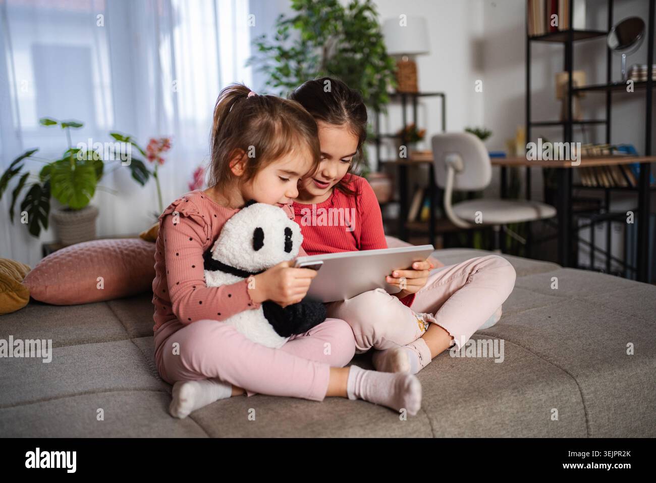 Sisters sharing digital tablet at home learning and playing Stock Photo