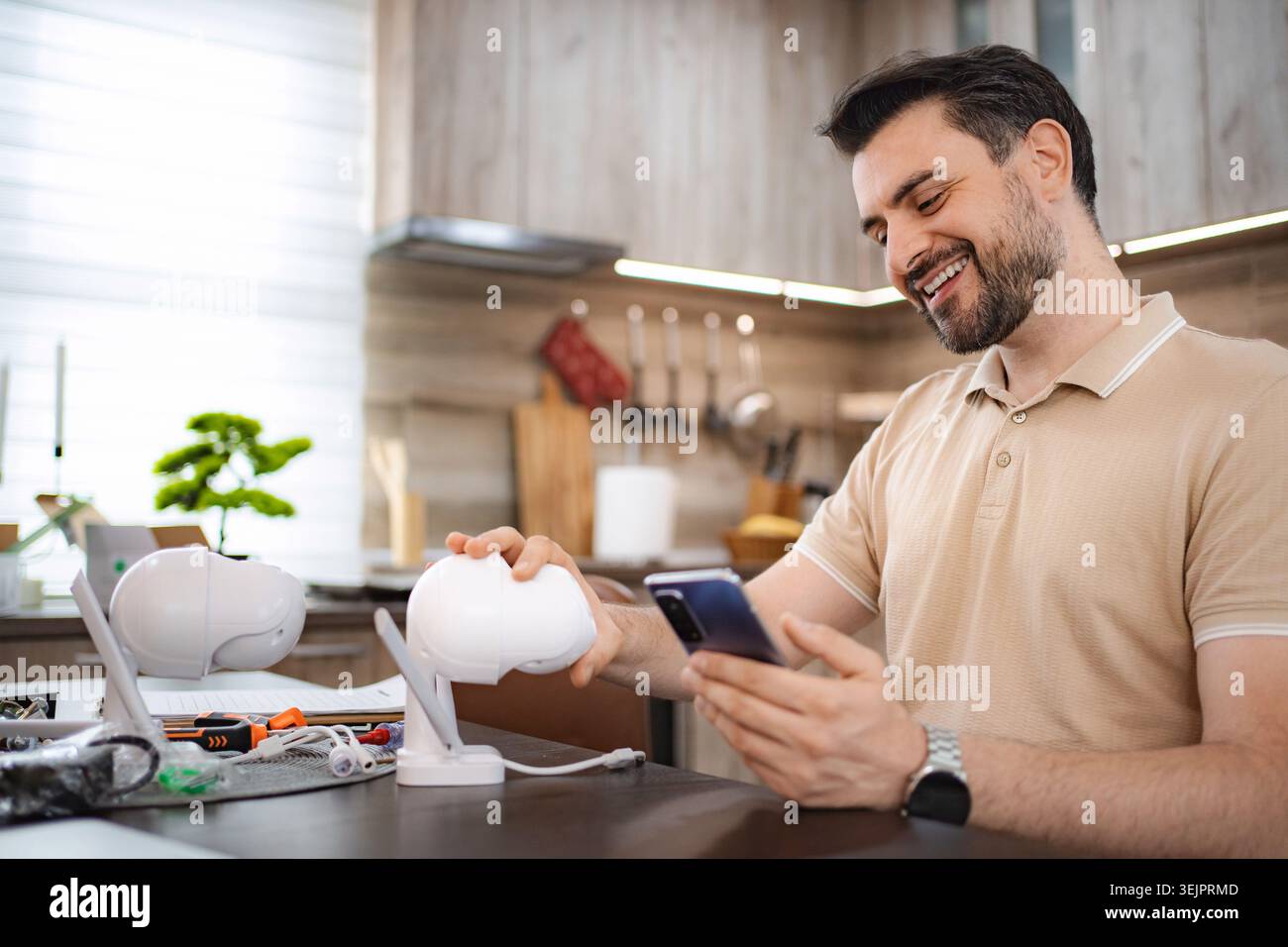 Man installing home security camera, connecting it to smartphone app Stock Photo