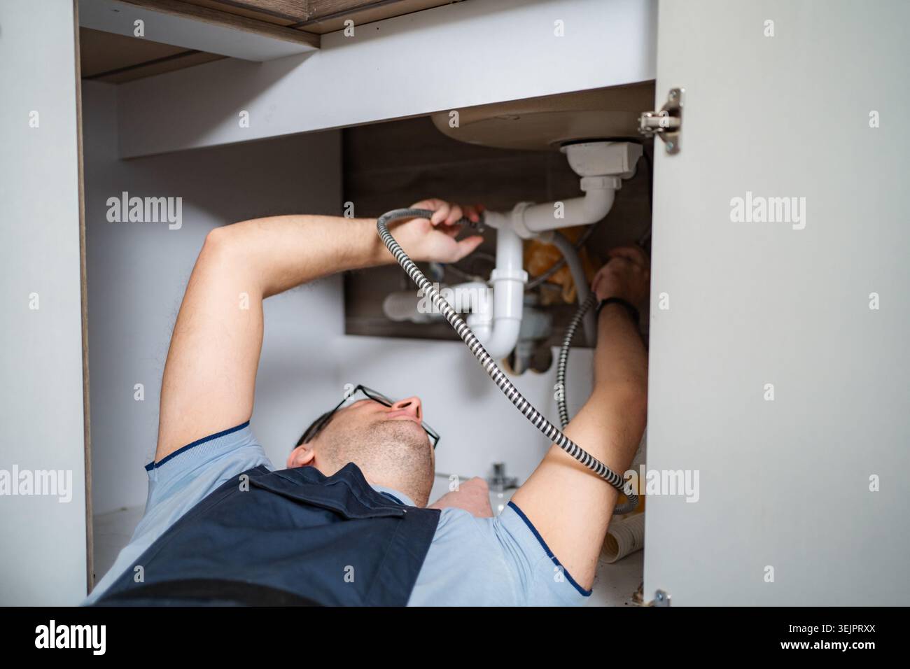 Plumber working on kitchen sink drain pipe system Stock Photo