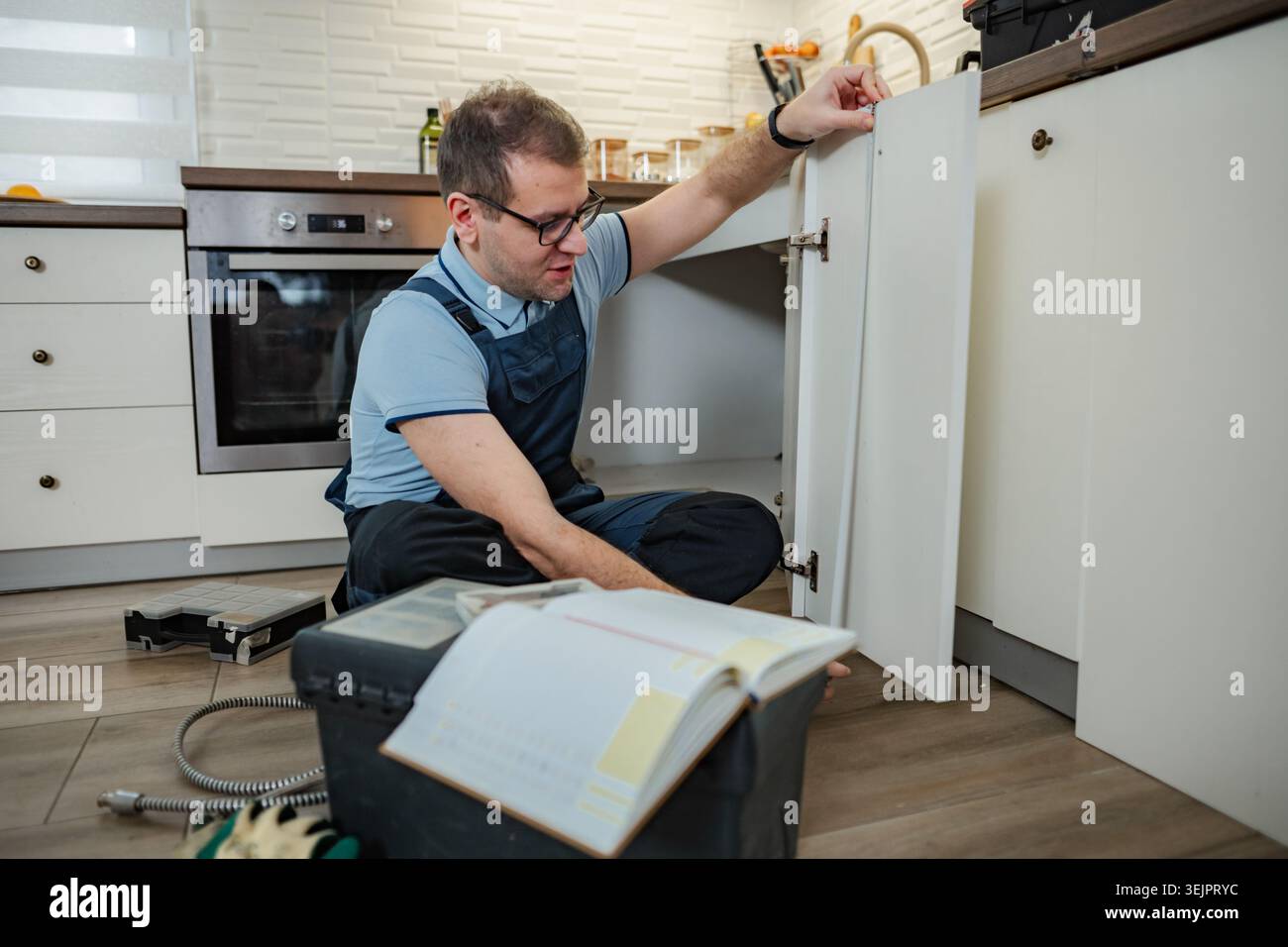 Handyman assembling kitchen cabinet in new home Stock Photo