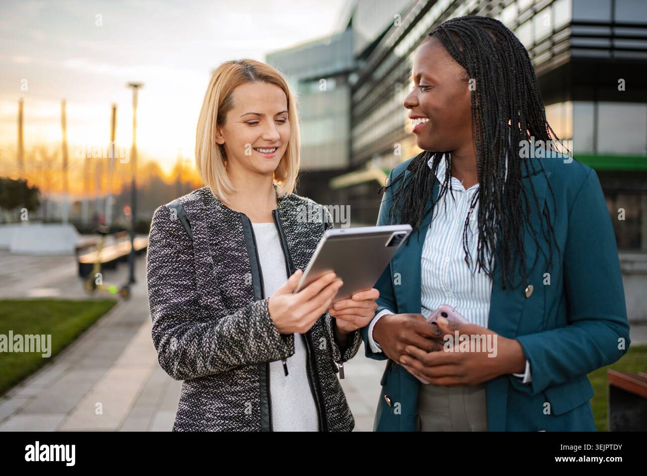 Businesswomen collaborating outdoors using digital tablet technology Stock Photo