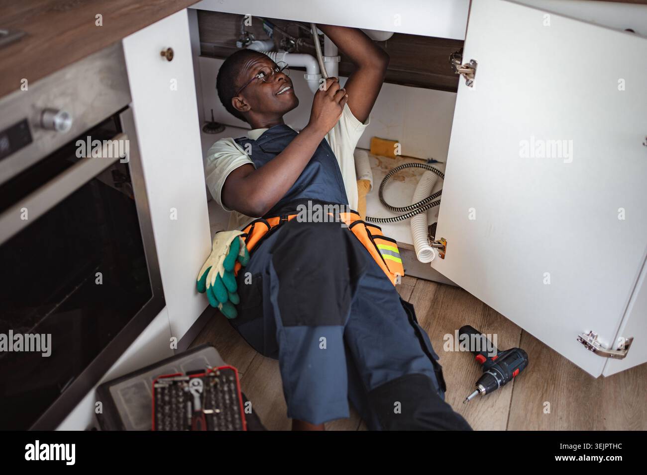 Plumber fixing pipes under kitchen sink Stock Photo