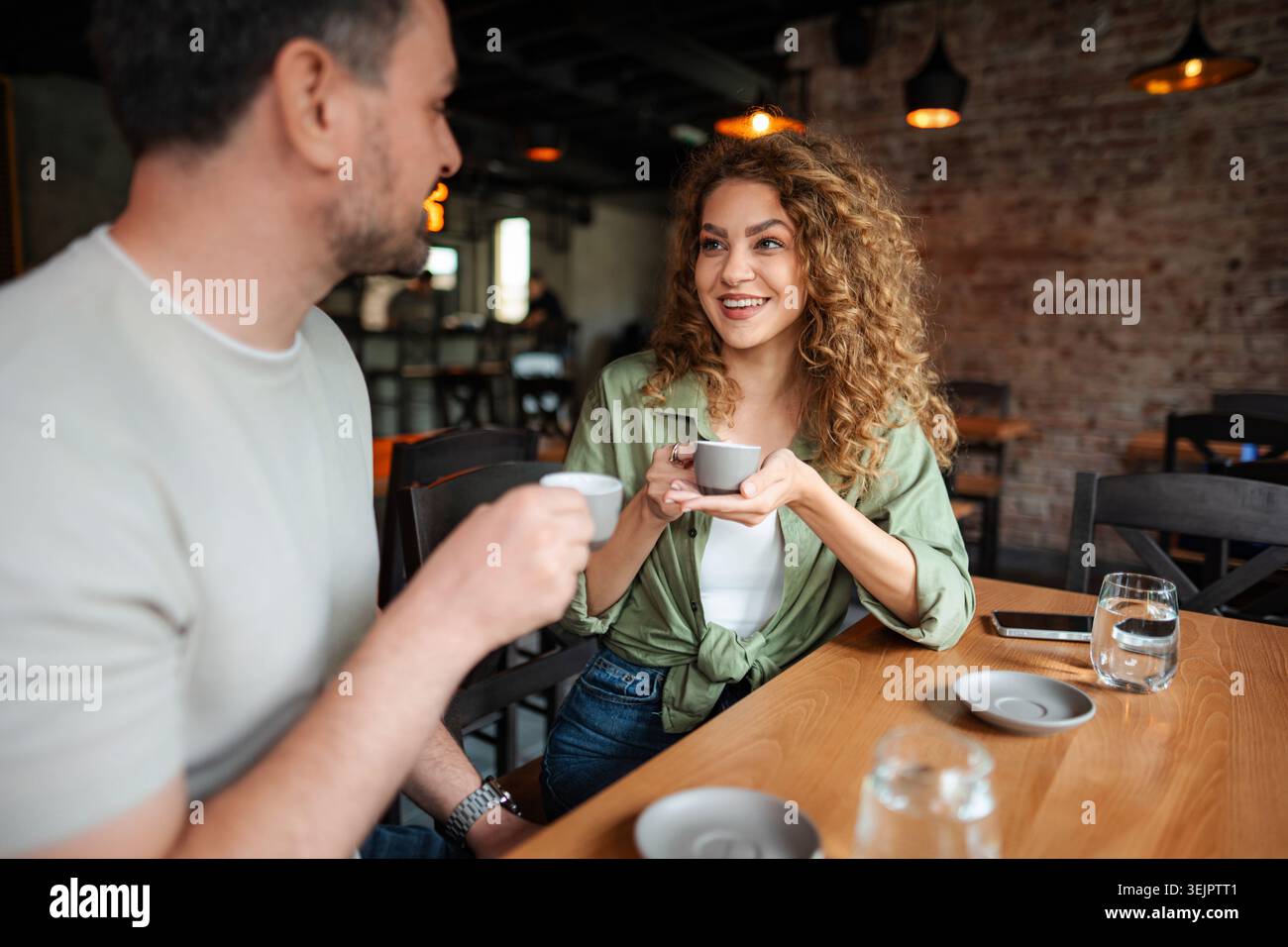 Young couple drinking coffee and talking in a cafe Stock Photo