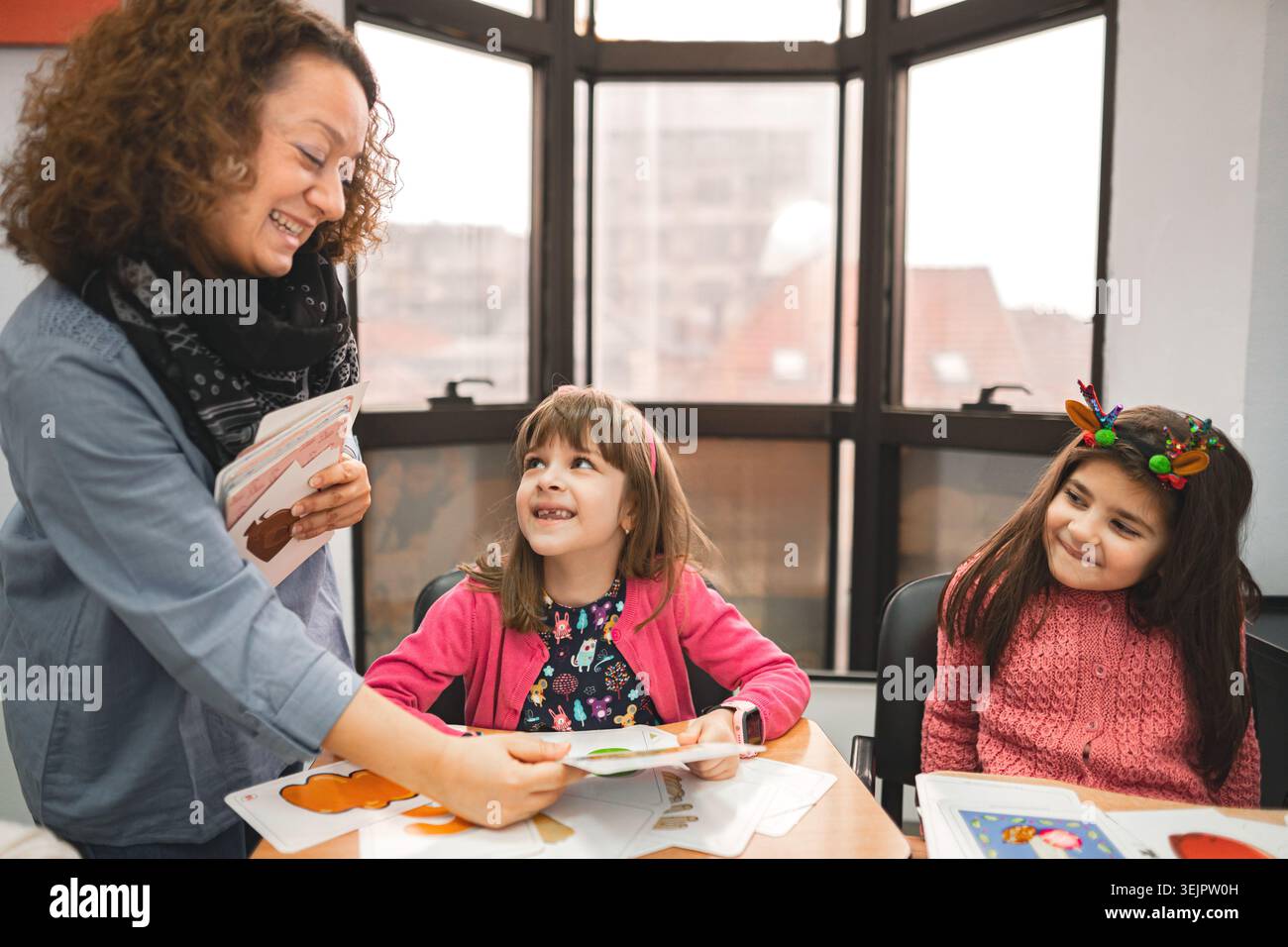 Female teacher helping elementary students at language school class Stock Photo