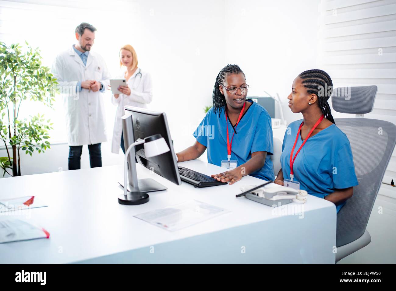 Healthcare team working on a computer and tablet in a modern clinic Stock Photo