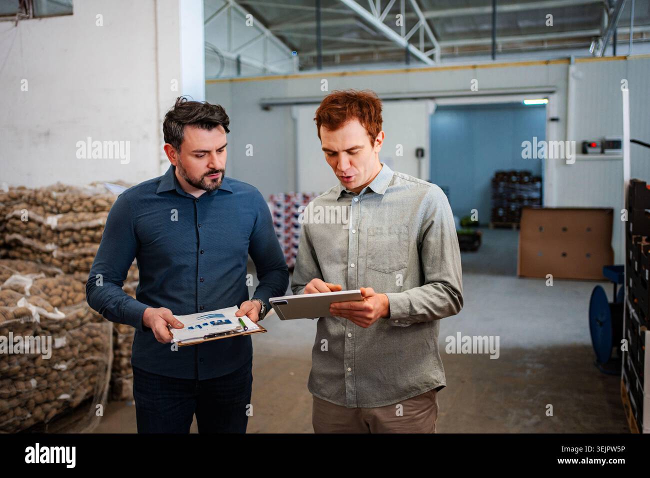 Warehouse managers analyzing data on digital tablet and clipboard Stock Photo