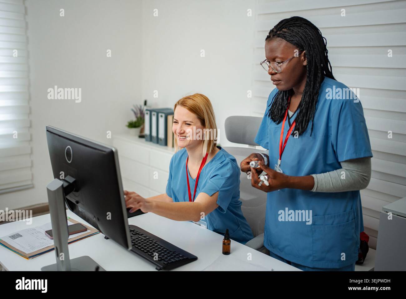 Diverse nurses collaborating on computer in modern medical office Stock Photo