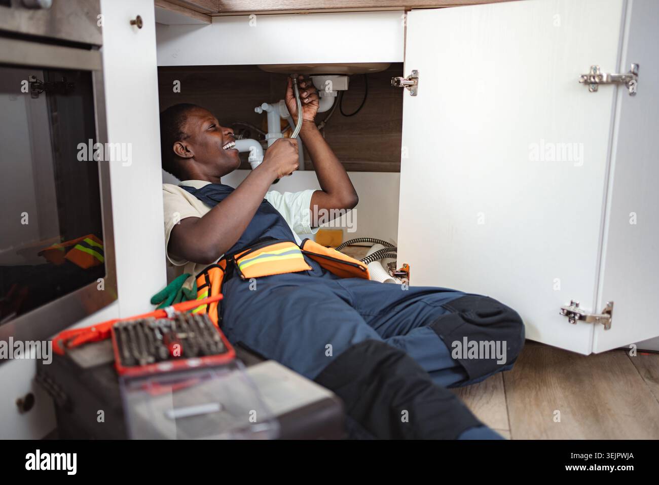 Plumber fixing pipes under kitchen sink Stock Photo