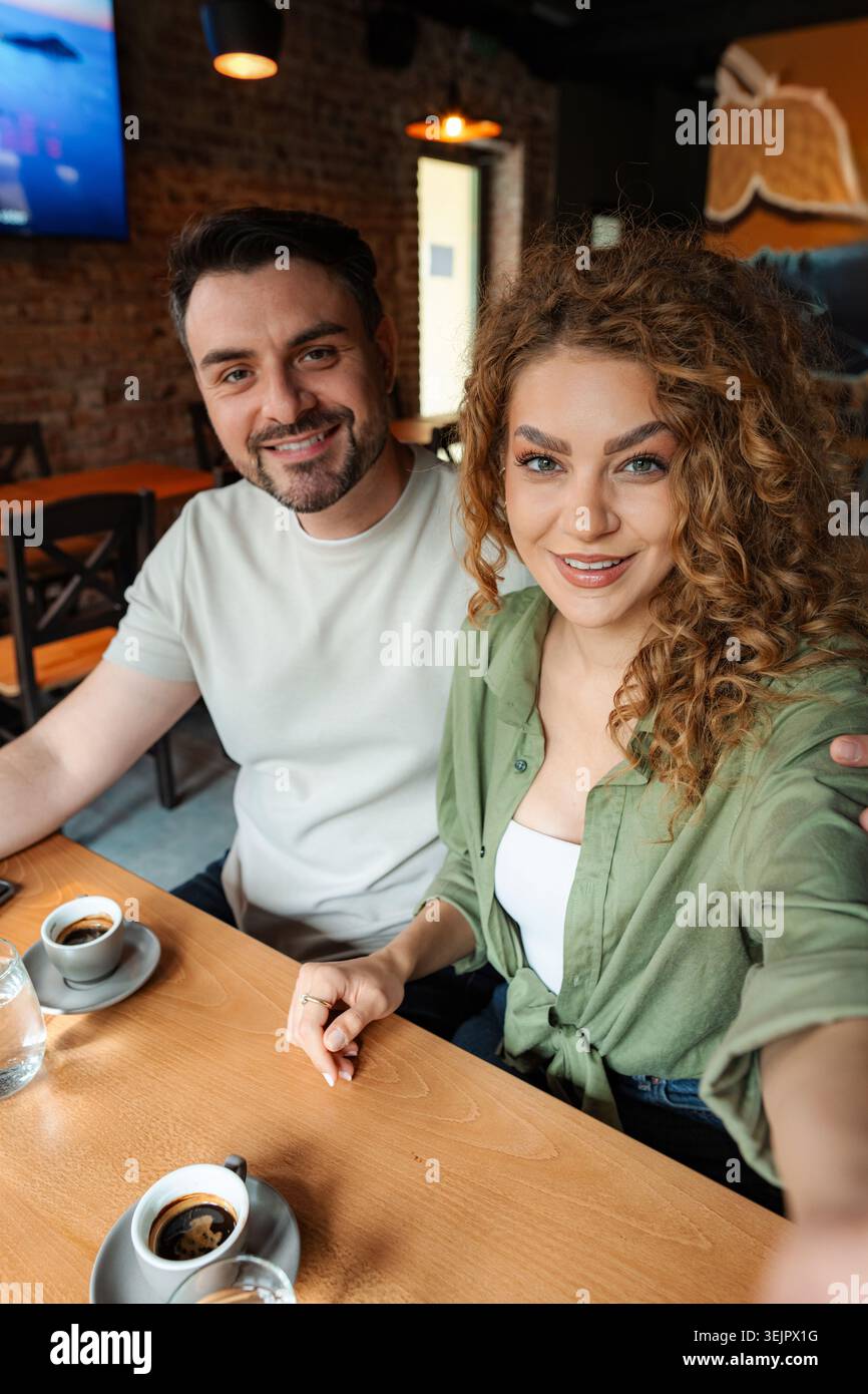 Young couple taking a selfie while having coffee in a cafe Stock Photo