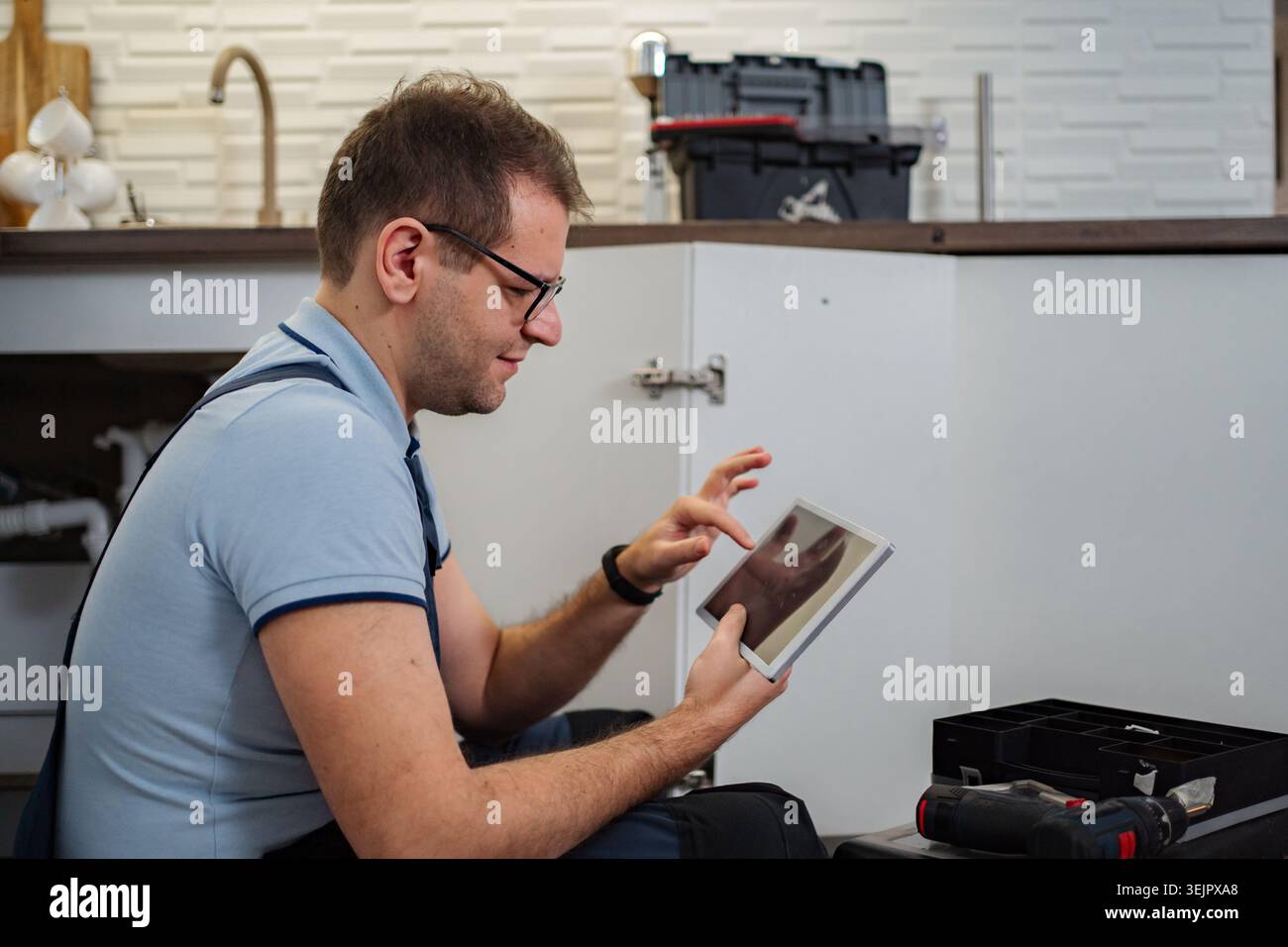 Plumber using tablet for kitchen sink repair Stock Photo