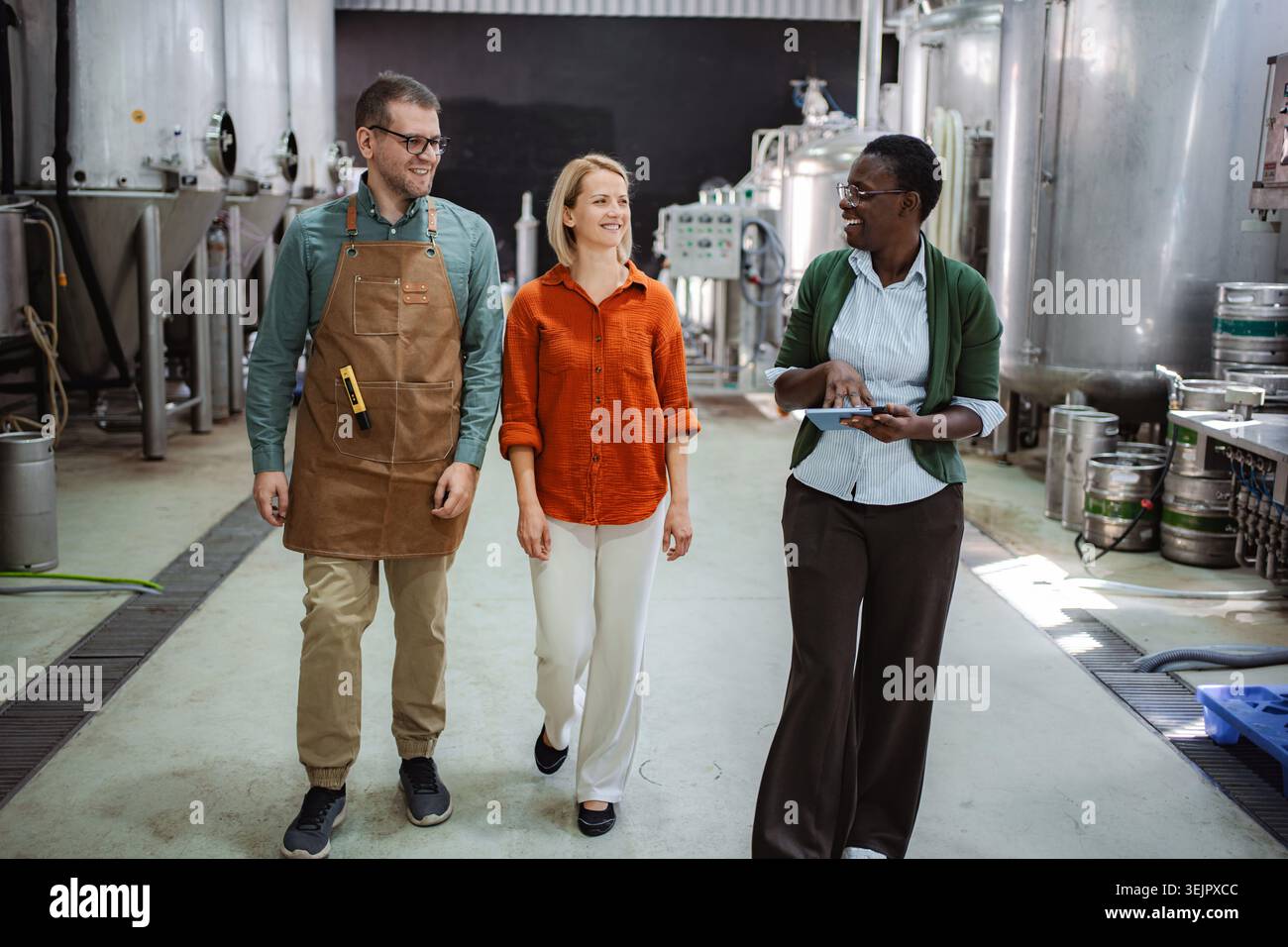 Colleagues walking through brewery discussing production process Stock Photo