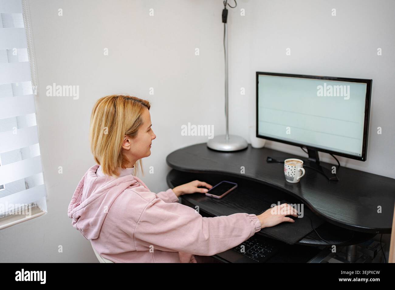 Young woman working from home using computer and mouse Stock Photo