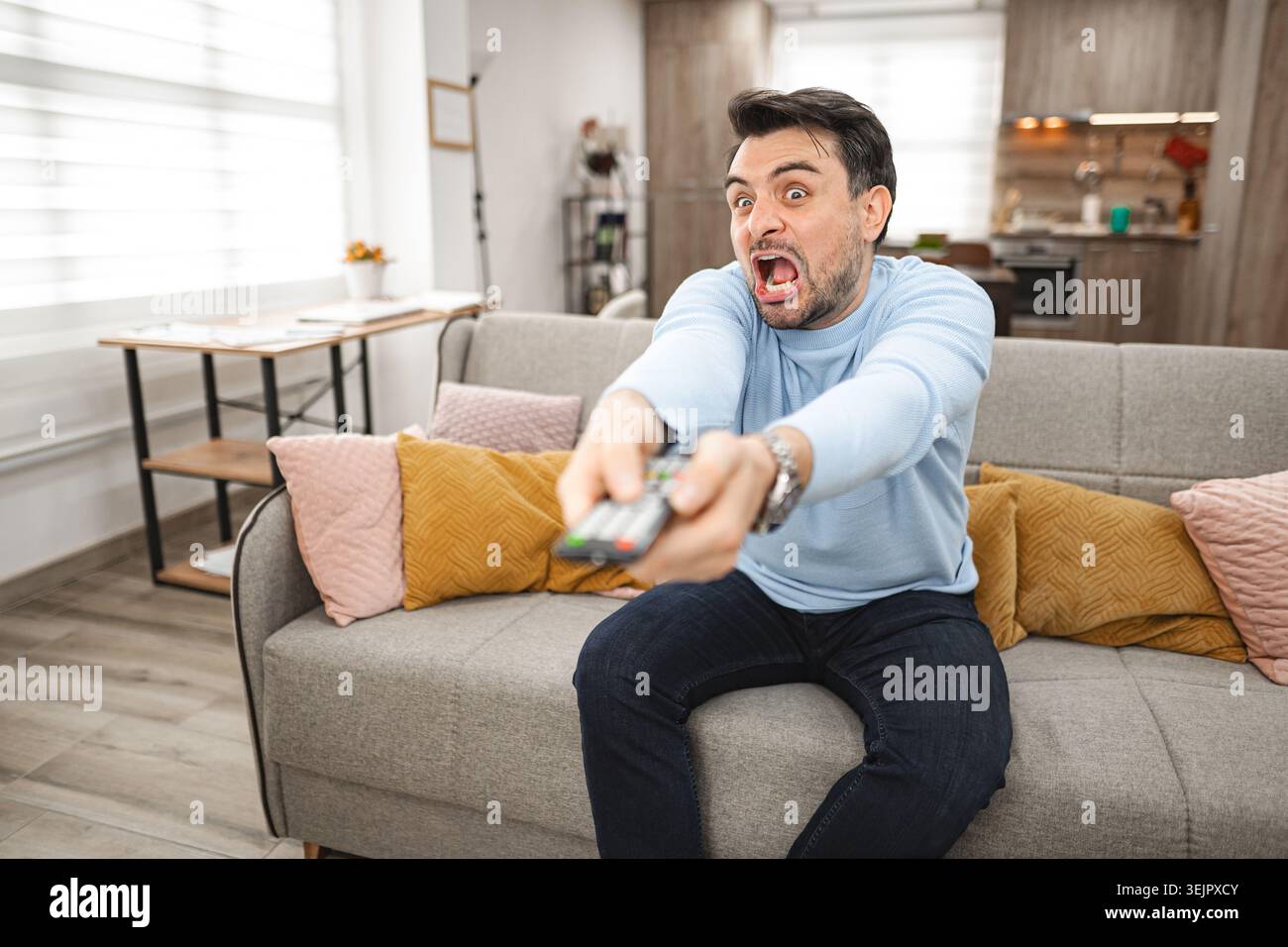 Man Sitting on Couch Holding Remote Stock Photo