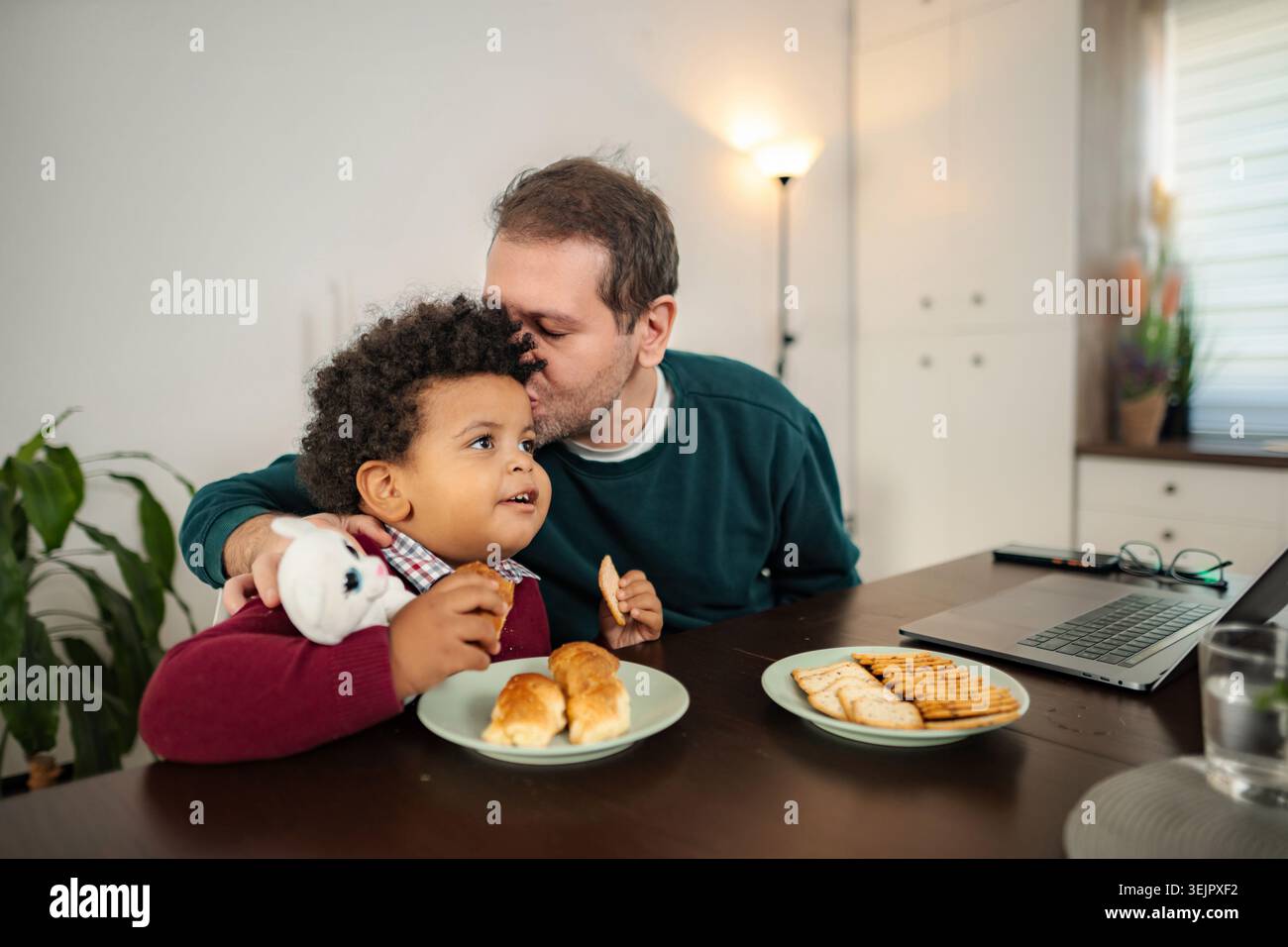 Father kissing son while having breakfast at home Stock Photo