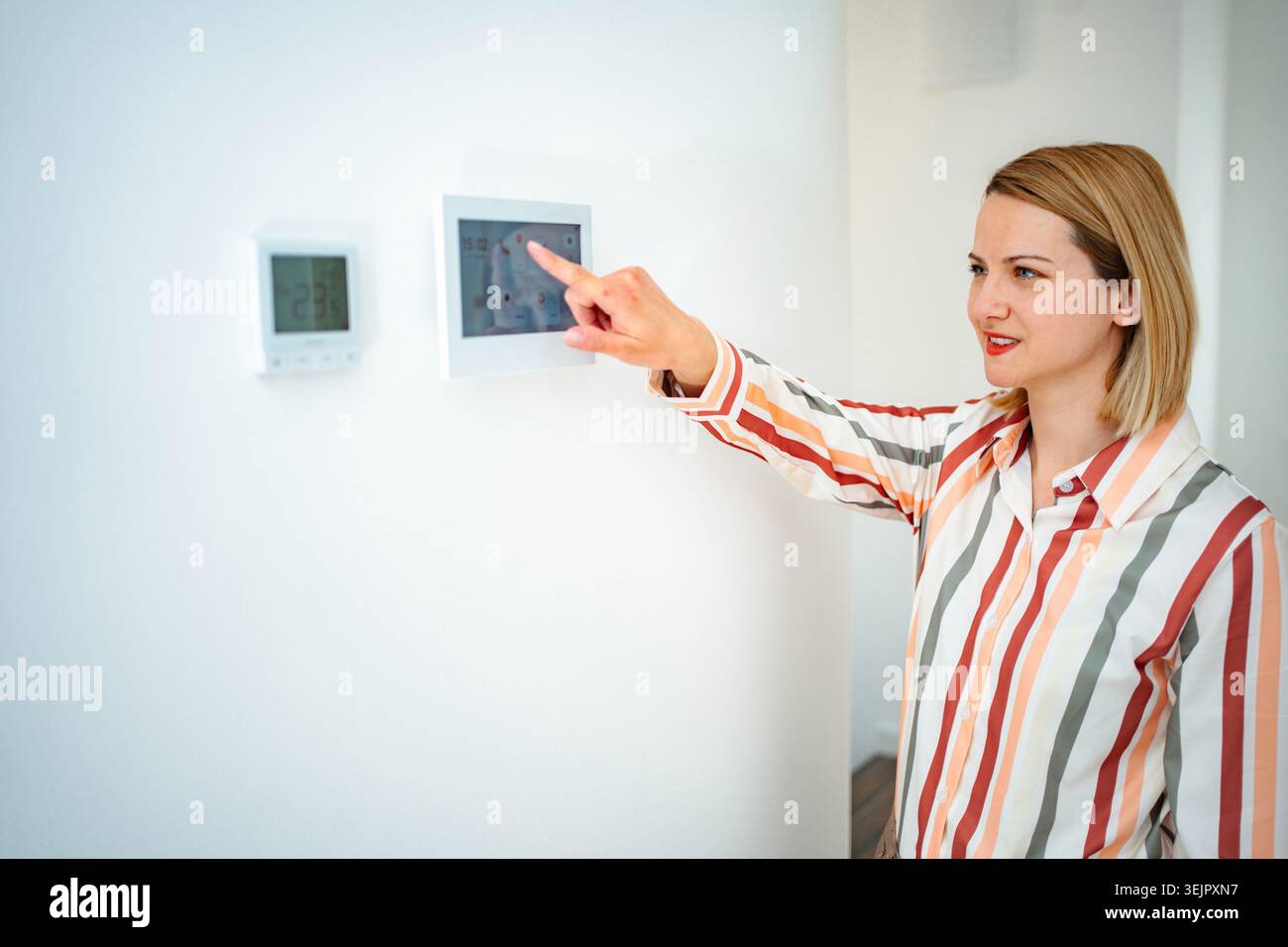 Woman using smart home control panel adjusting climate indoors Stock Photo