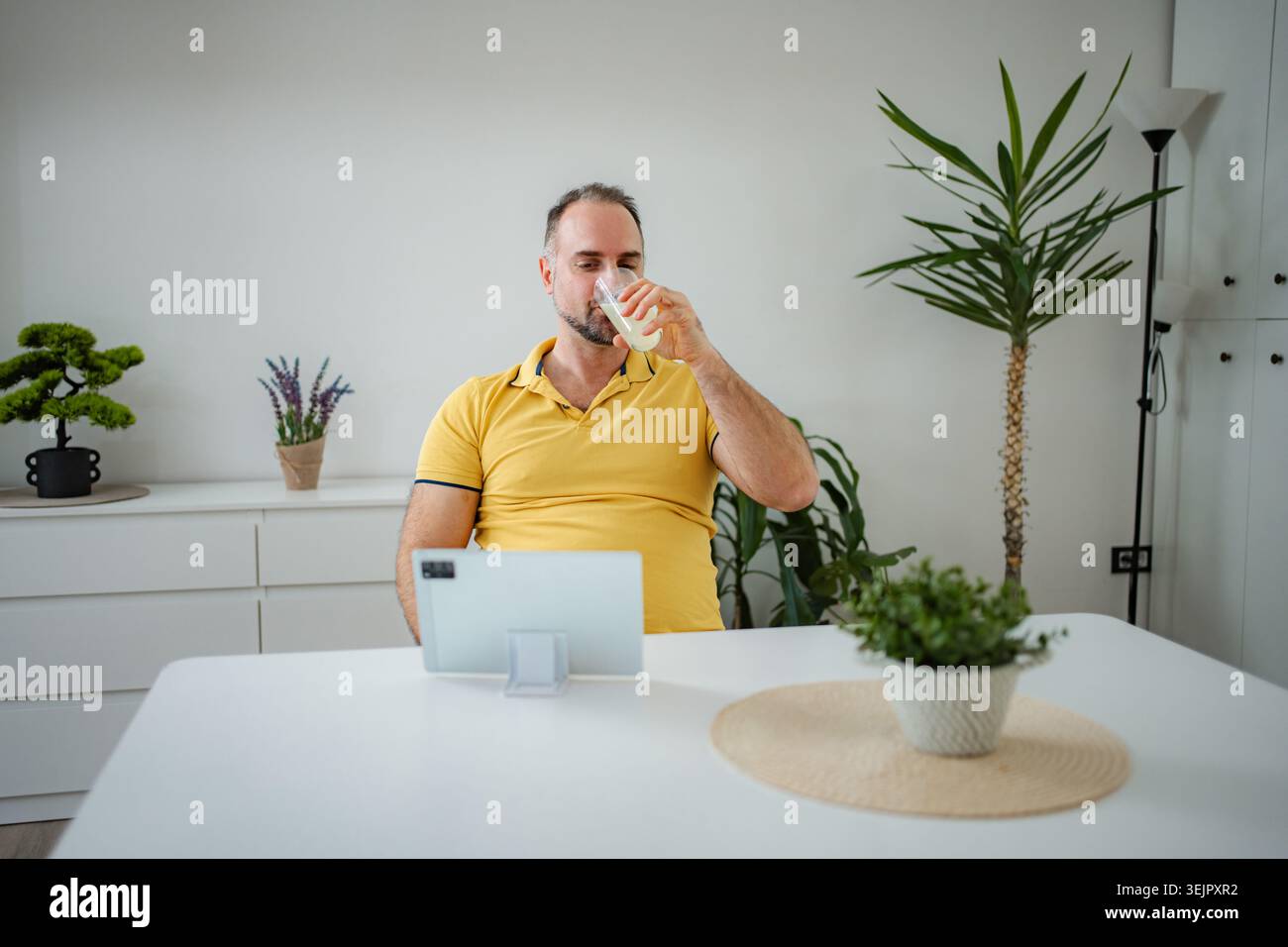 Man drinking juice while using tablet at home Stock Photo