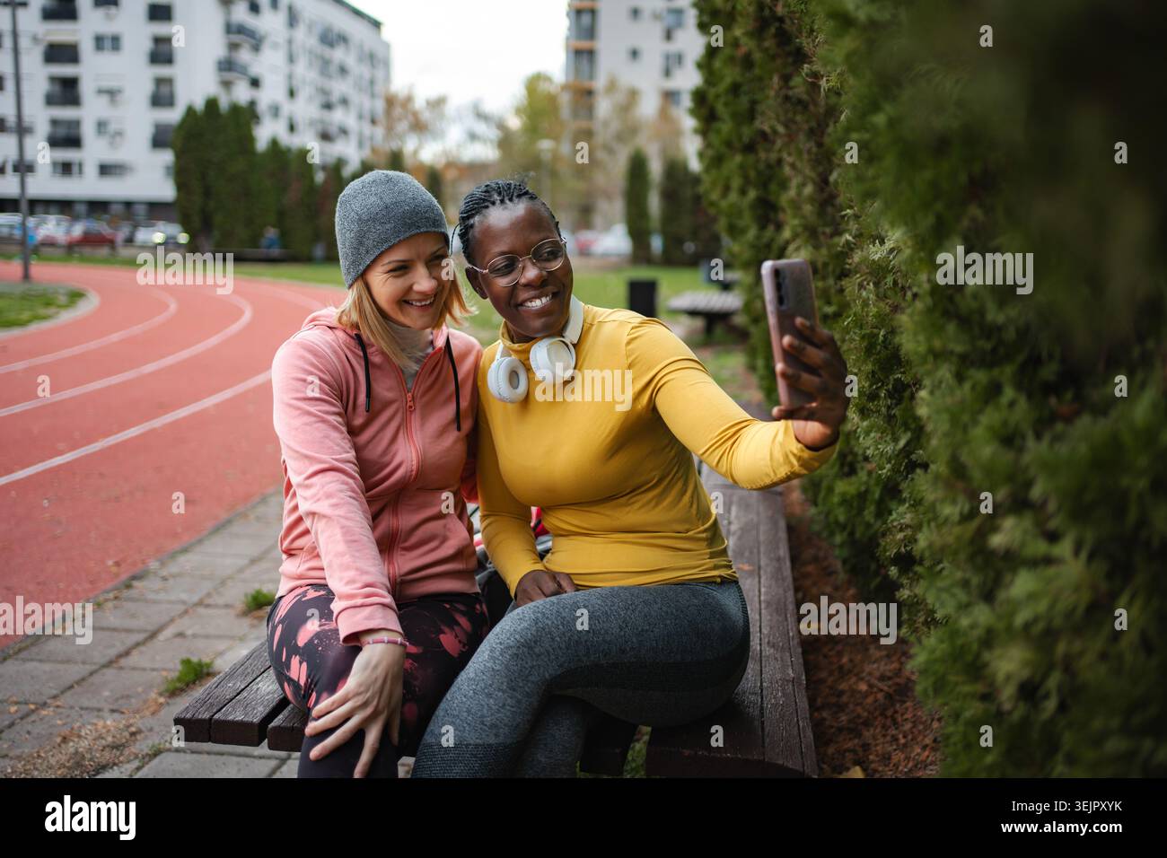 Diverse friends taking selfie sitting on bench outdoors Stock Photo