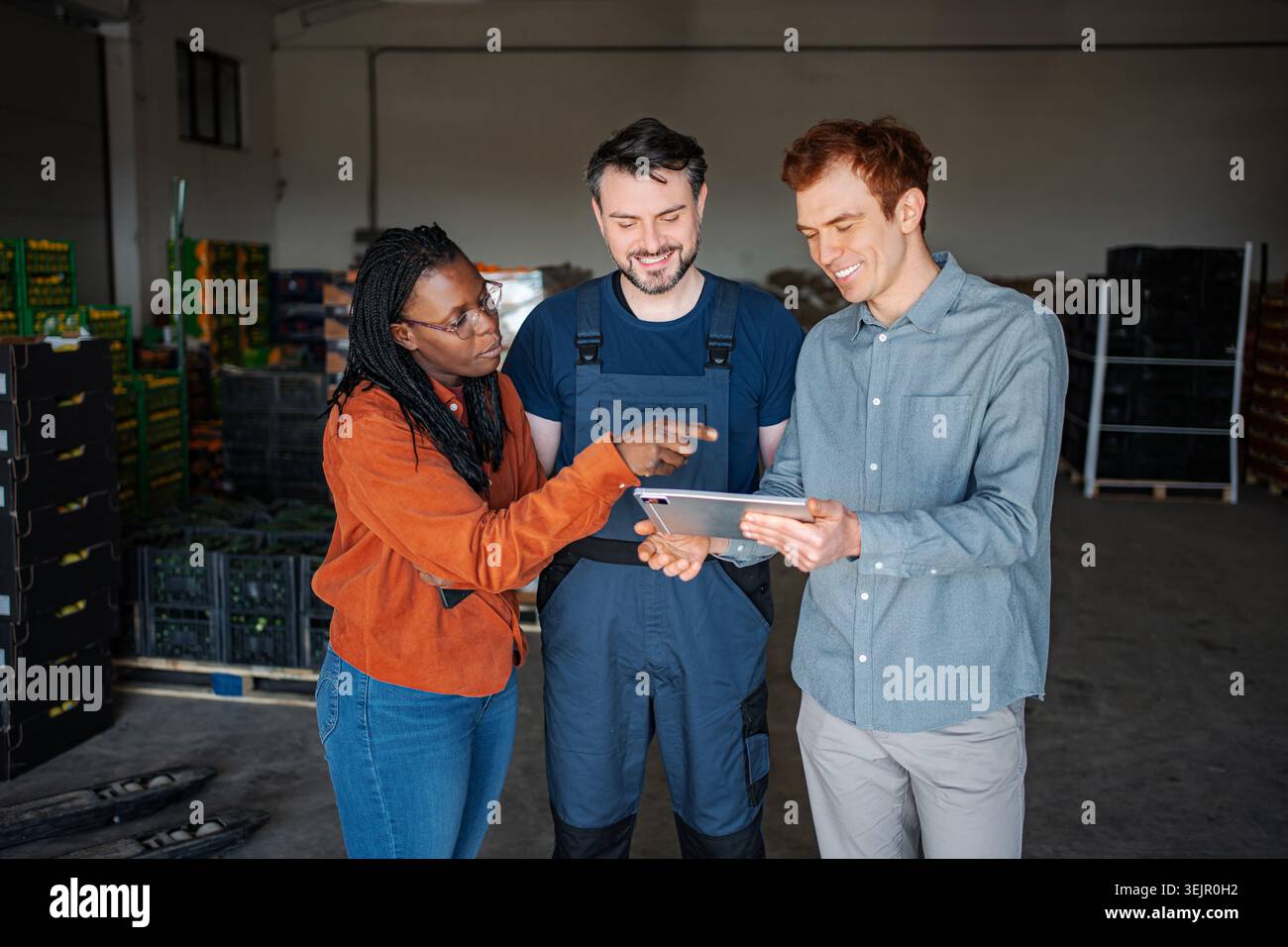 Warehouse workers discussing inventory on digital tablet in storage facility Stock Photo