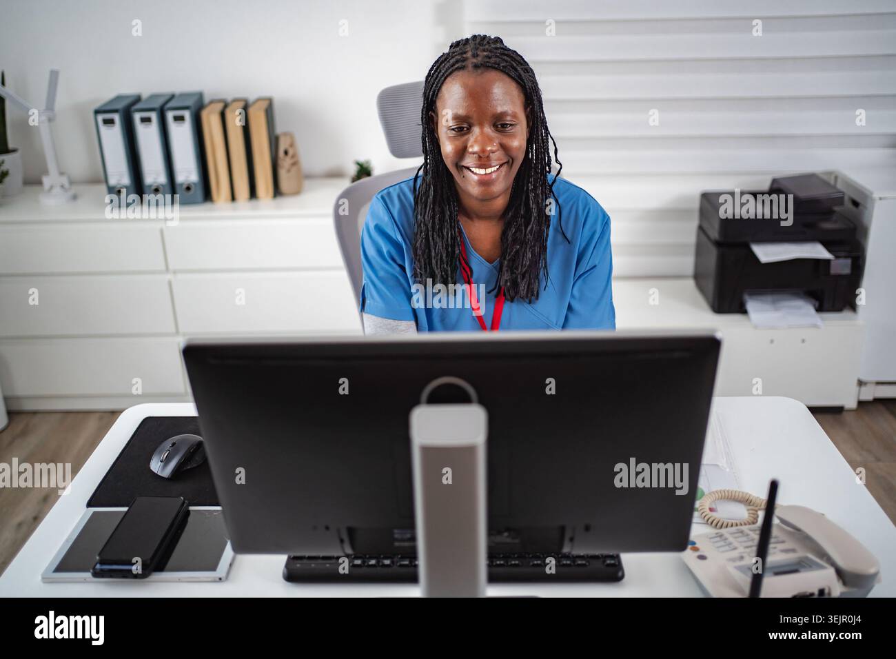 Female medical professional smiling while working on computer Stock Photo
