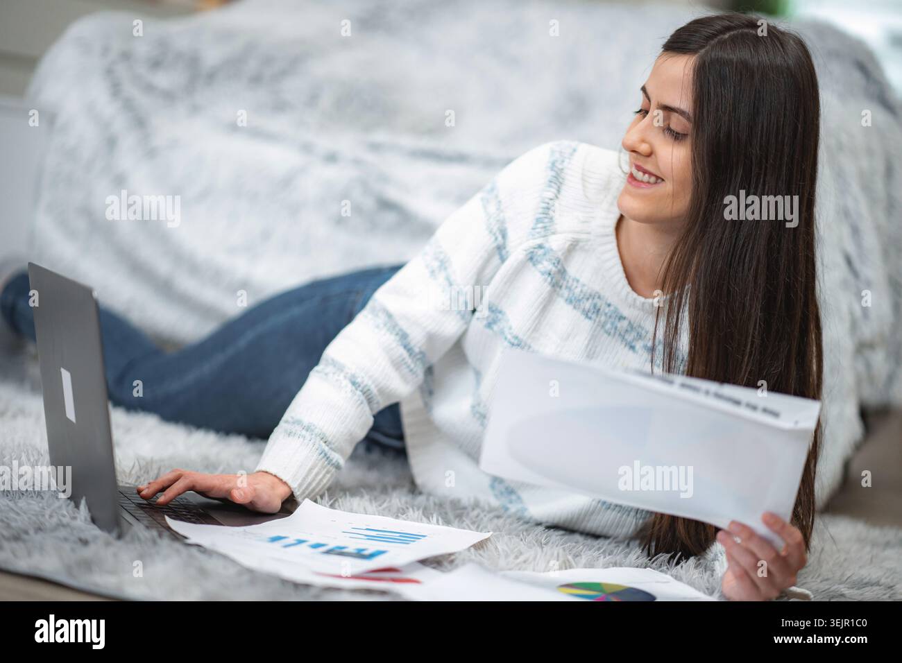 Woman freelancer working from home on laptop with documents Stock Photo