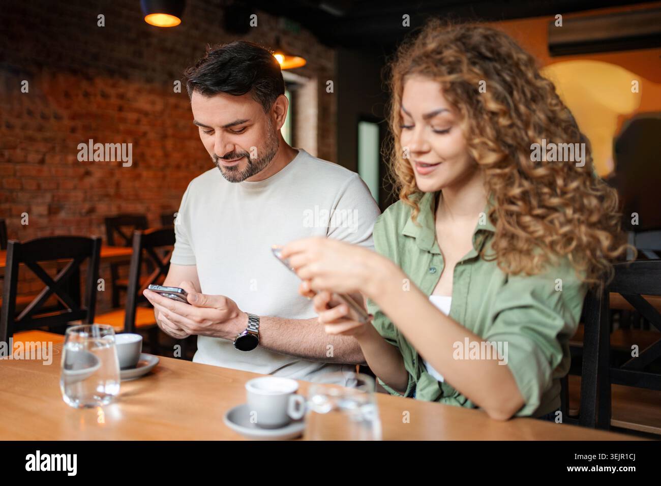 Couple using smartphones in a cafe, ignoring each other Stock Photo