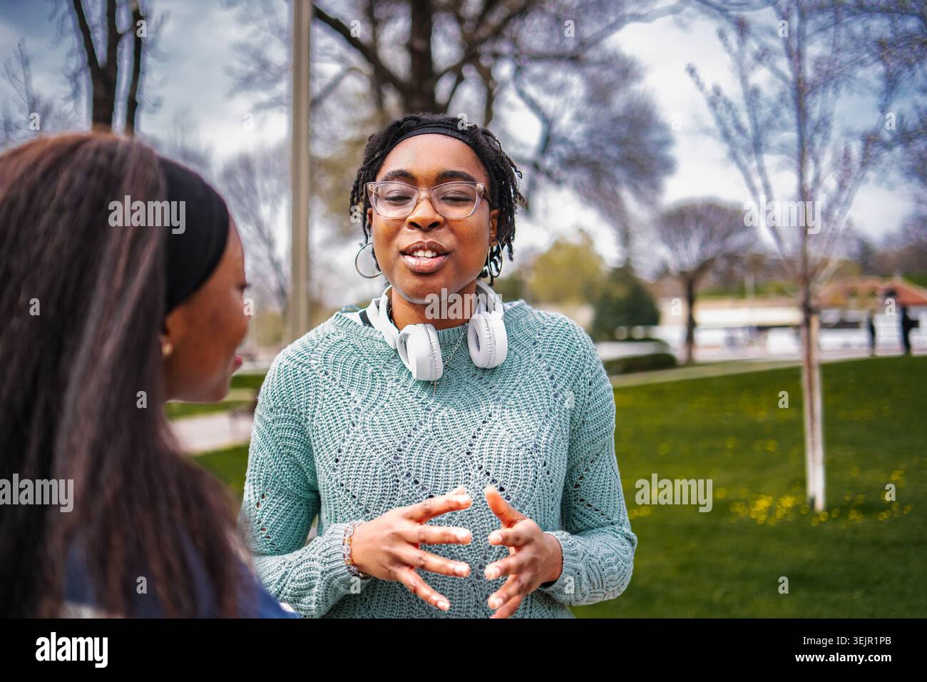 Two young adult women having a conversation in a park setting Stock Photo
