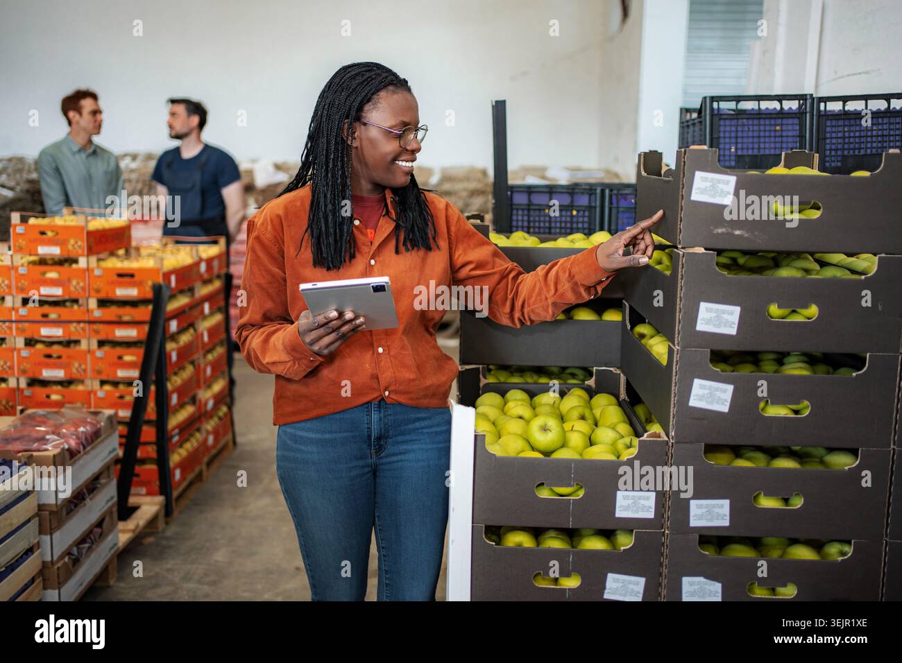 Female worker checking apple inventory in warehouse with tablet Stock Photo