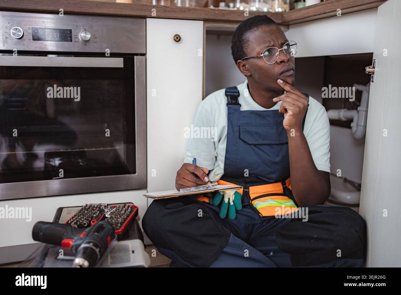 Plumber inspecting pipes and taking notes in kitchen Stock Photo