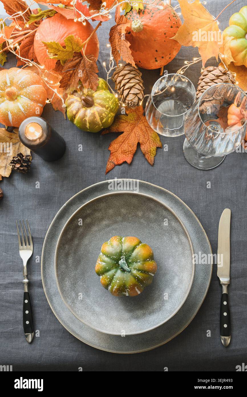 Thanksgiving day table setting with plate decorated fallen leaves, pumpkins. Stock Photo