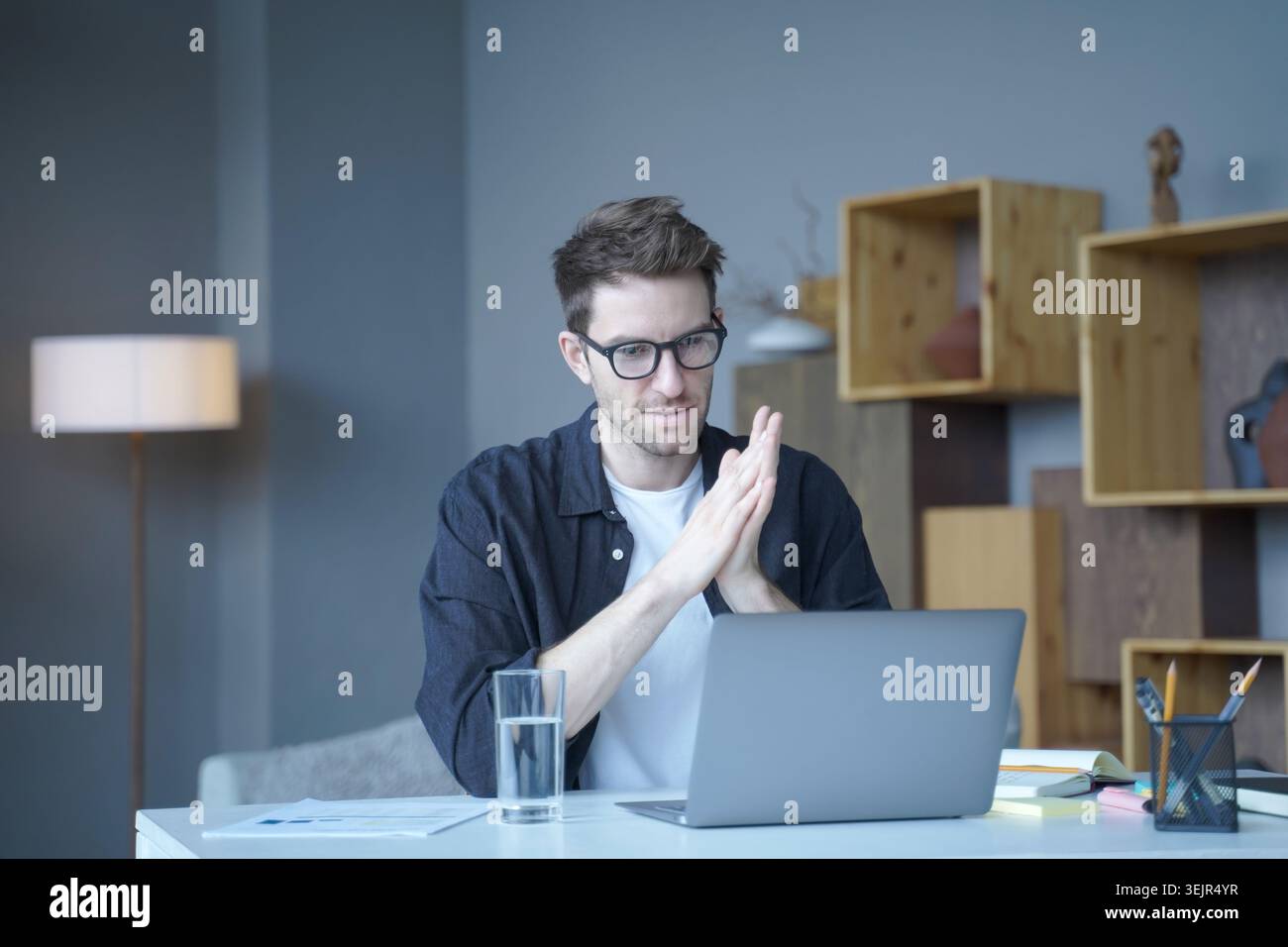 Young handsome austrian male freelancer wearing glasses looking at computer screen attentively Stock Photo