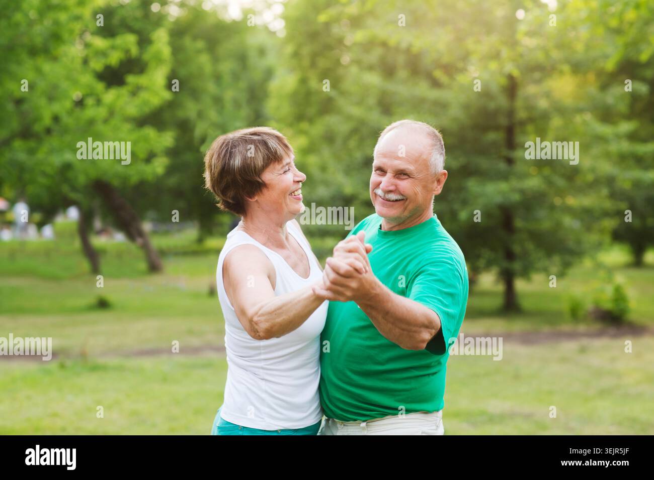 Senior couple dancing in park on sunny day Stock Photo
