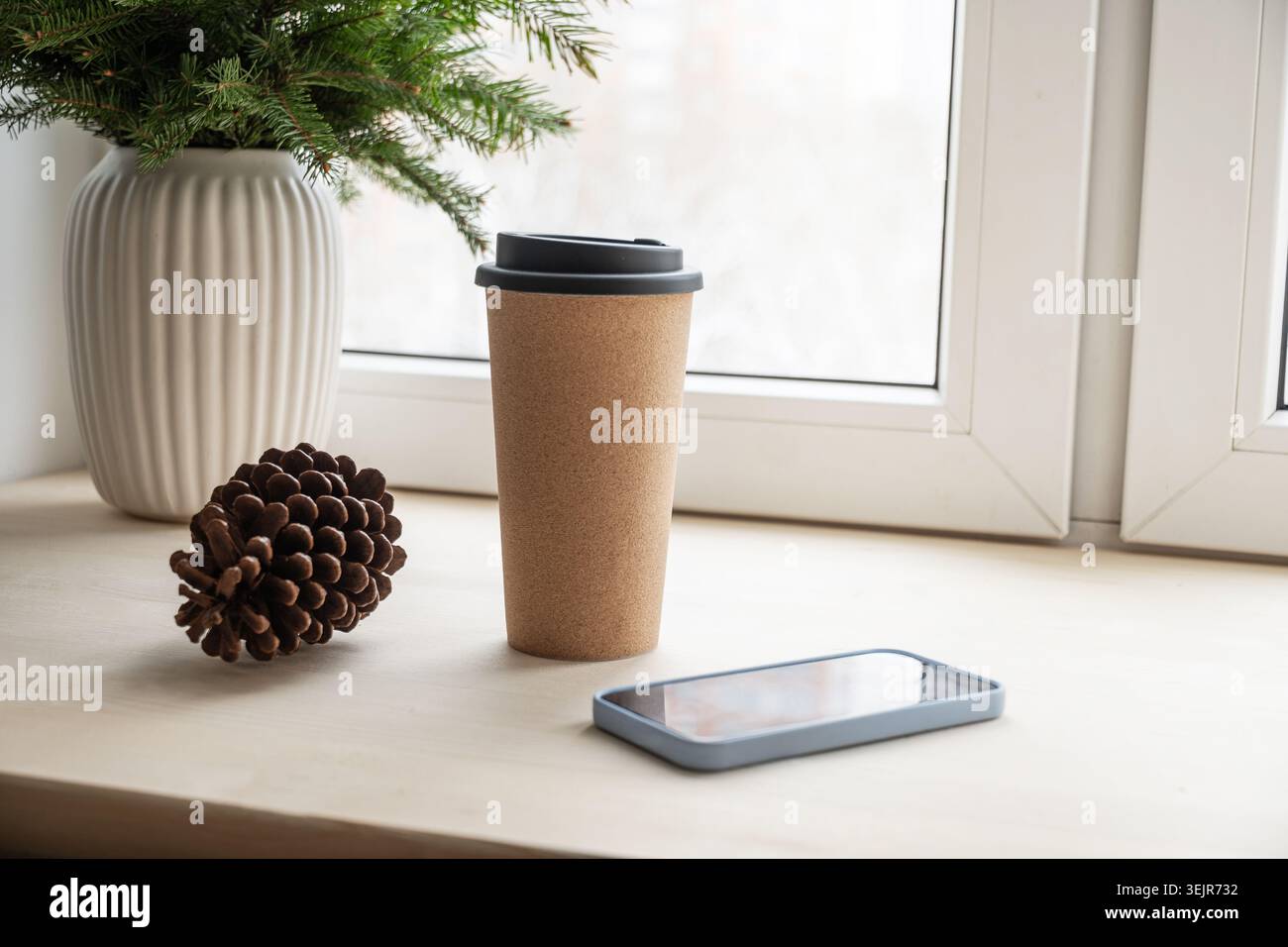 Eco reusable coffee cup and smartphone on windowsill Stock Photo