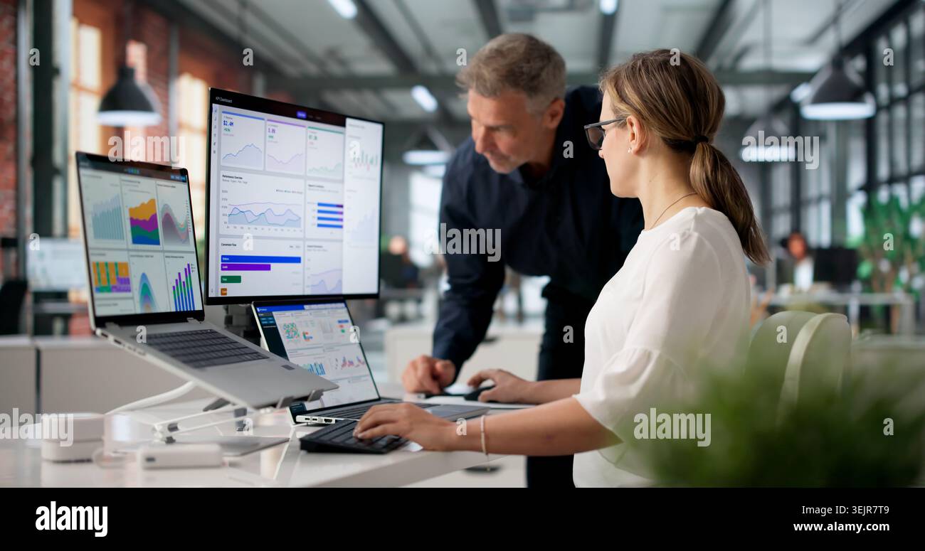 Two Financial Analysts Working Together, Reviewing Data On Dashboard. Stock Photo