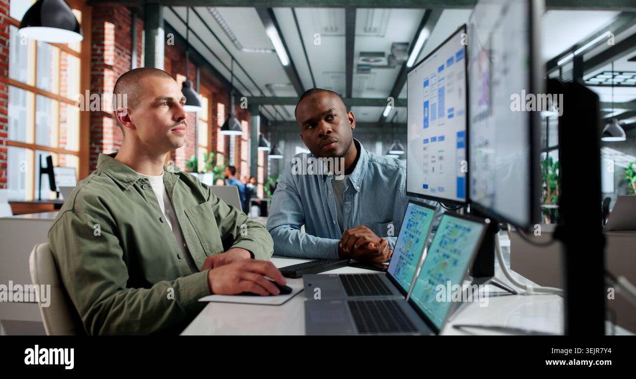 Two Young UX Designers Work Together On App Interface Using Laptops. Stock Photo